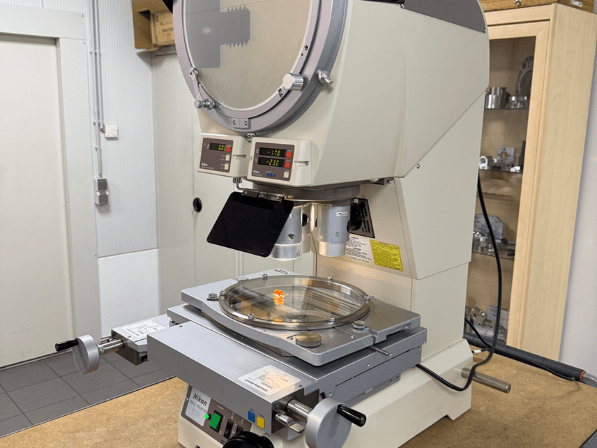 Nikon modelio mikroskopas iš priekio su skaitmeniniais ekranais, reguliuojamu staliuku ir apskrita stikline plokštele.