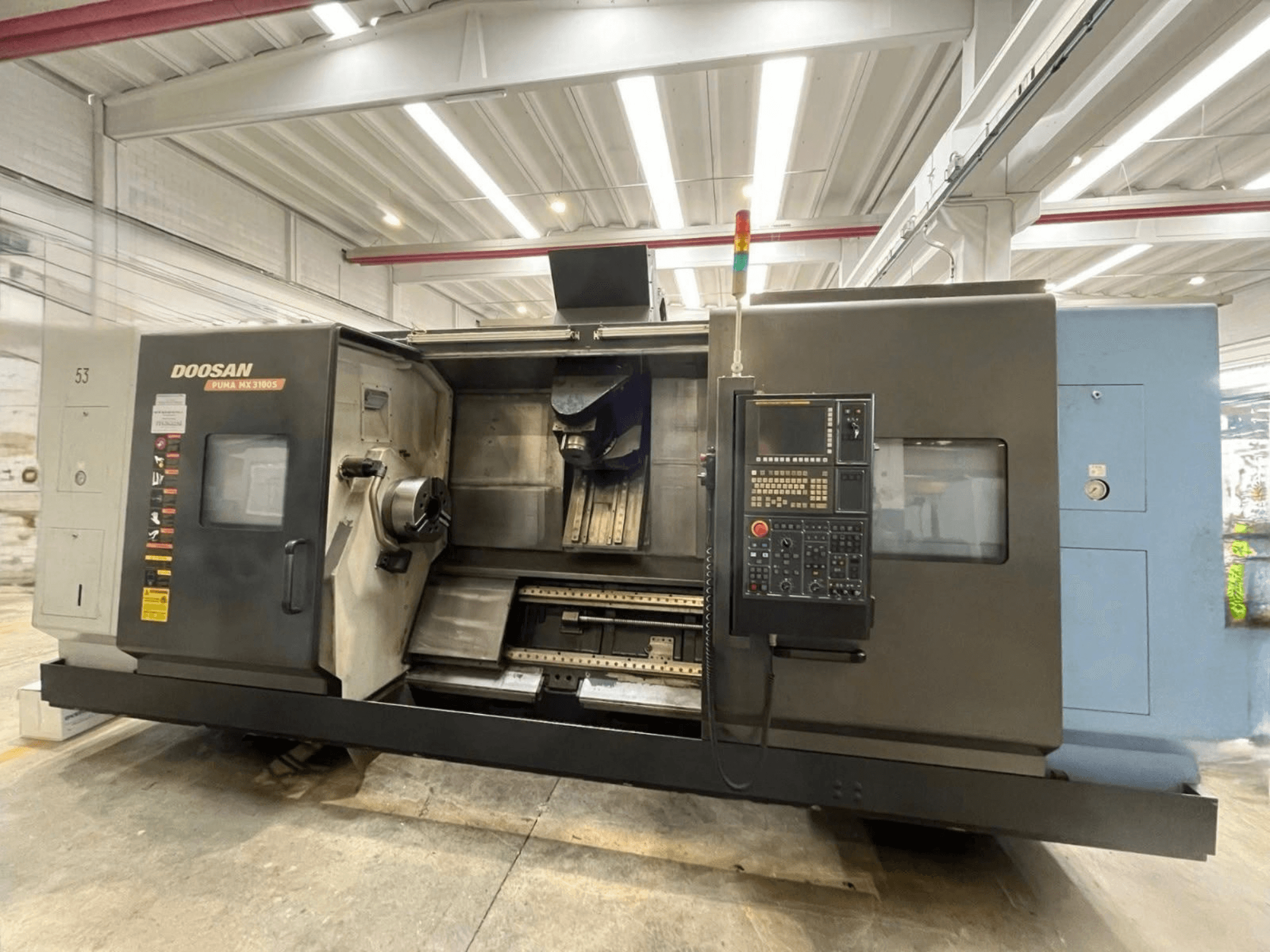 „DOOSAN PUMA MX3100“ horizontalios tekinimo staklių vaizdas iš priekio, kuriame matomas valdymo pultas bei suktuko ir įrankių laikiklio zona.