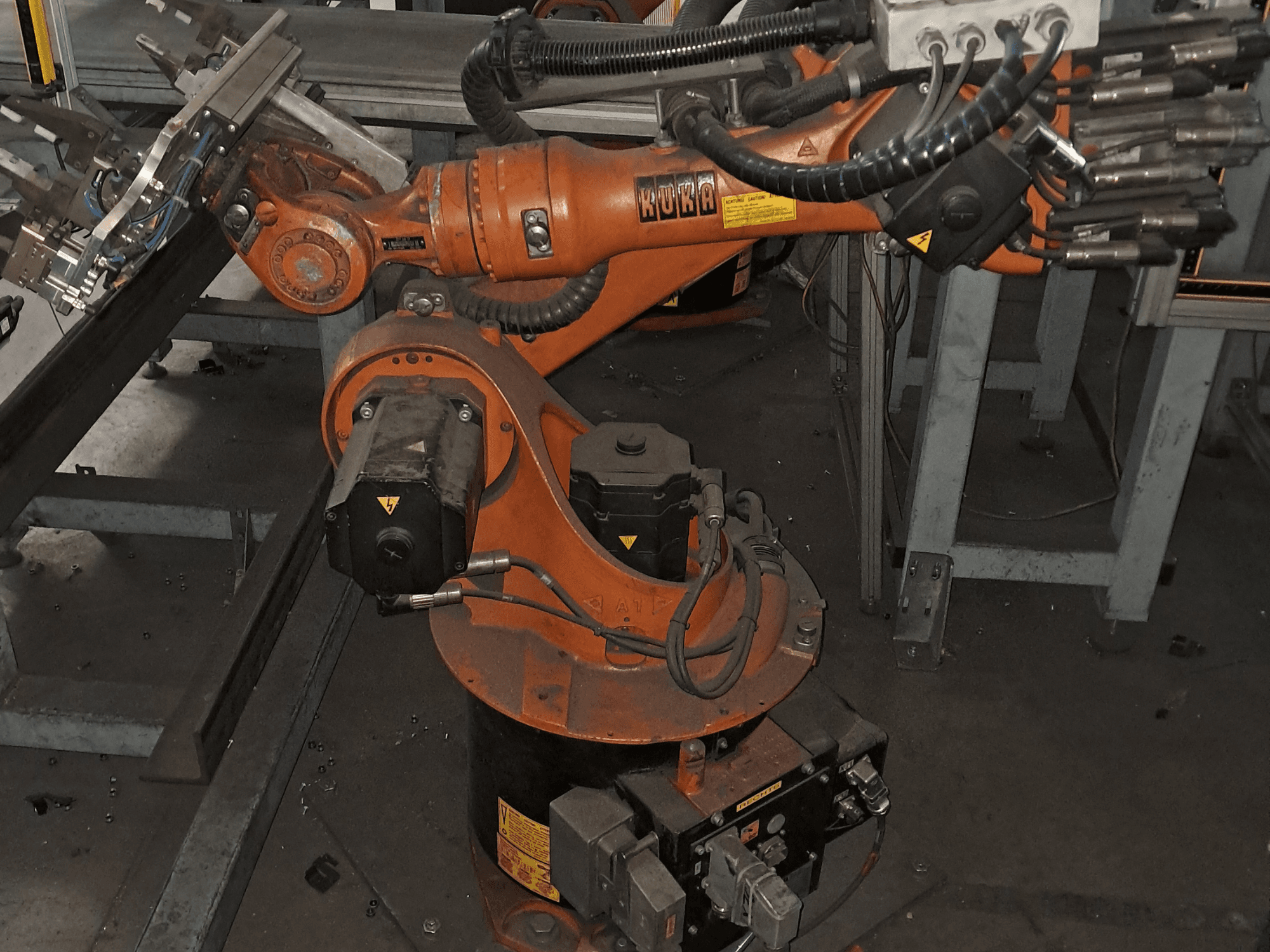„KUKA KR 16-2“ roboto ranka, vaizduojama iš viršaus, kur matyti oranžinis korpusas, variklis ir mechaniniai komponentai.