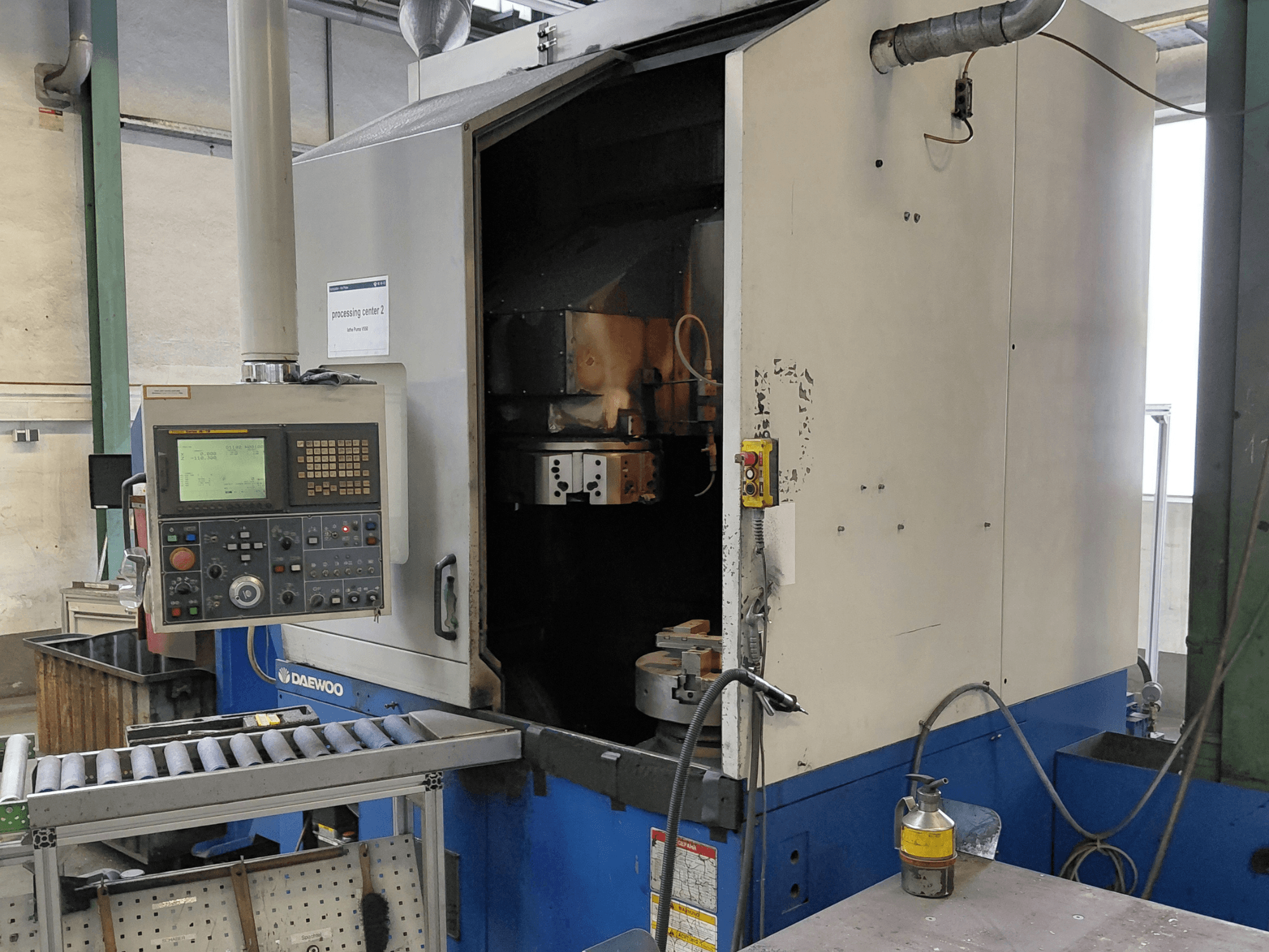 Vertikalios tekinimo staklės "Daewoo Puma V550", priekinis vaizdas, kuriame matyti valdymo skydelis, suklys ir aušinimo skysčio jungtis.