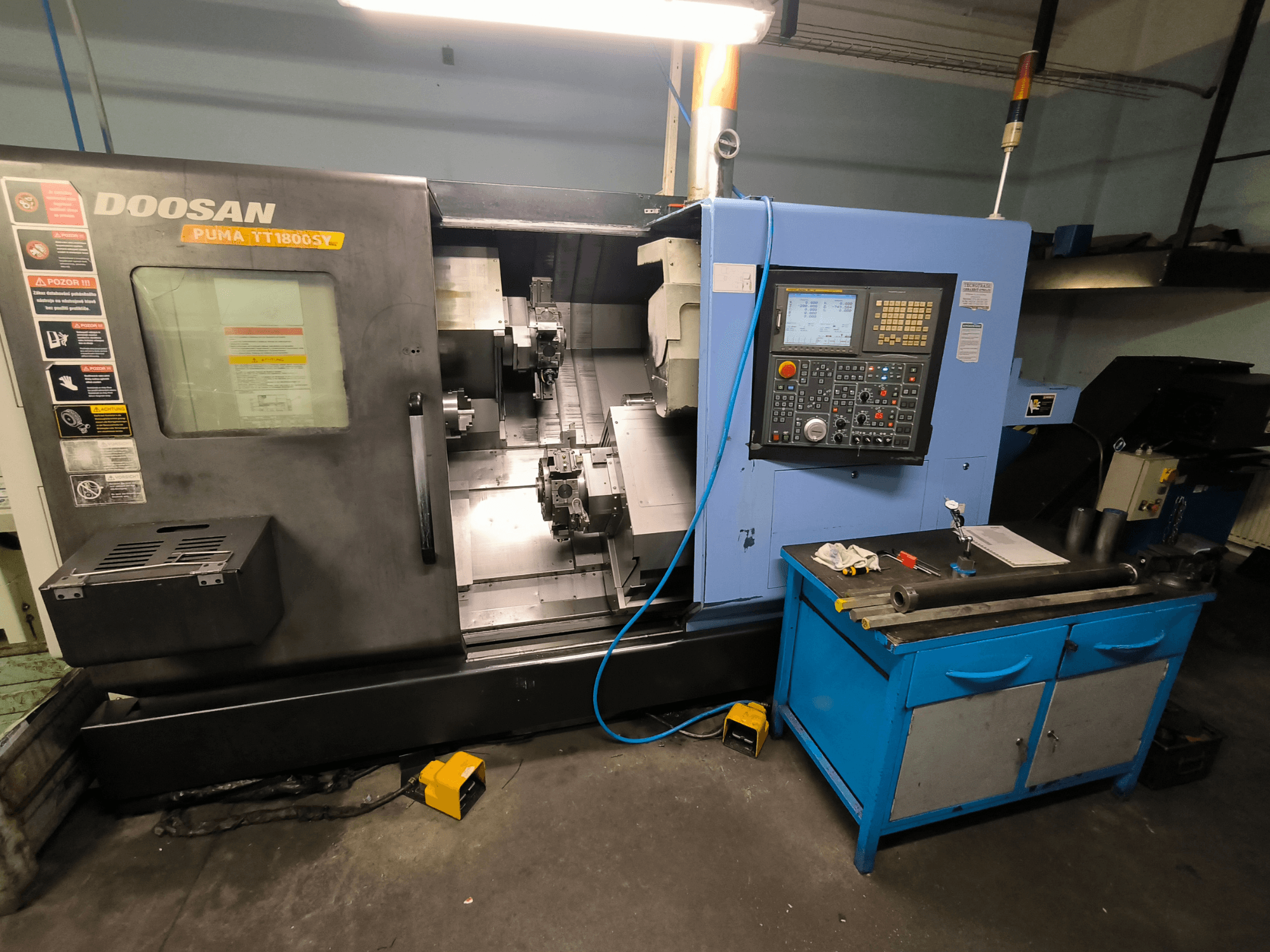 "Doosan Puma TT1800SY" CNC tekinimo staklės, vaizdas iš priekio, kuriame matomas valdymo skydelis, darbo zona su įrankiais ir staklių komponentai.