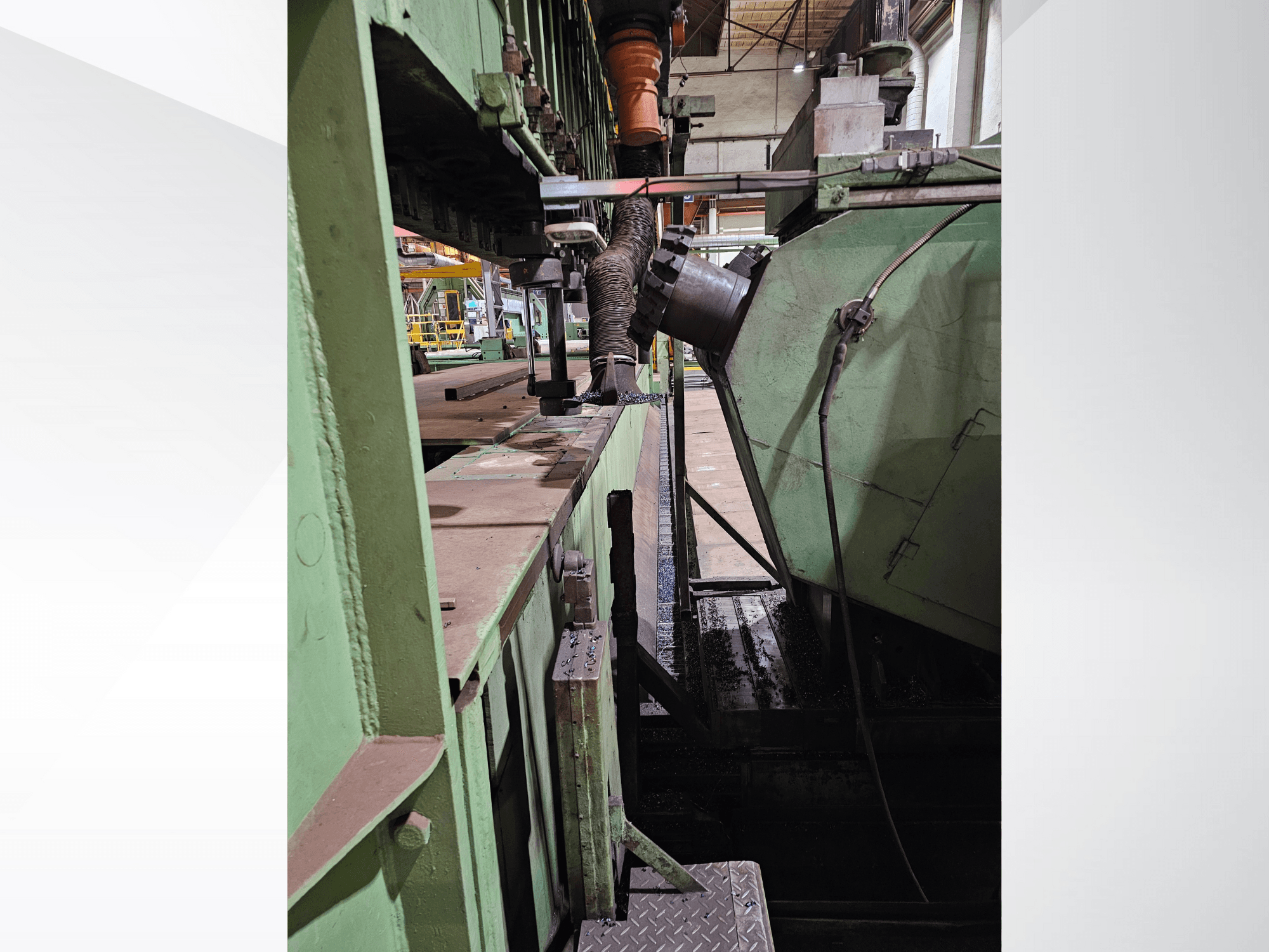 Žalios spalvos pramoninės mašinos su bunkerio ir padavimo mechanizmo vaizdu iš šono, demonstruojant metalinius komponentus ir platformą.