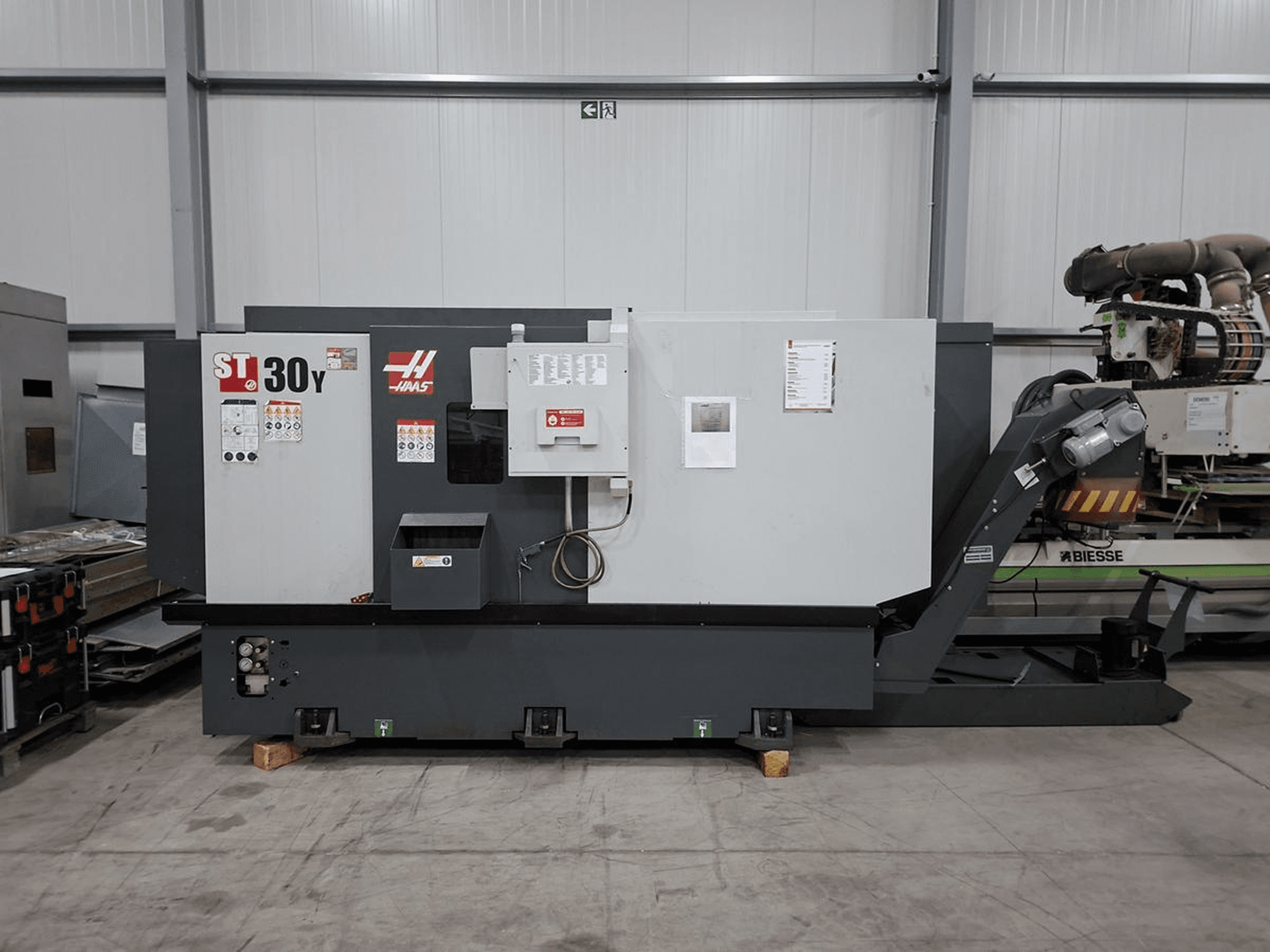 „Haas ST-30Y“ horizontaliojo tekinimo staklių vaizdas iš šono, kuriame matomi valdymo elementai, užrašai ir tvirta konstrukcija erdvioje dirbtuvėje.