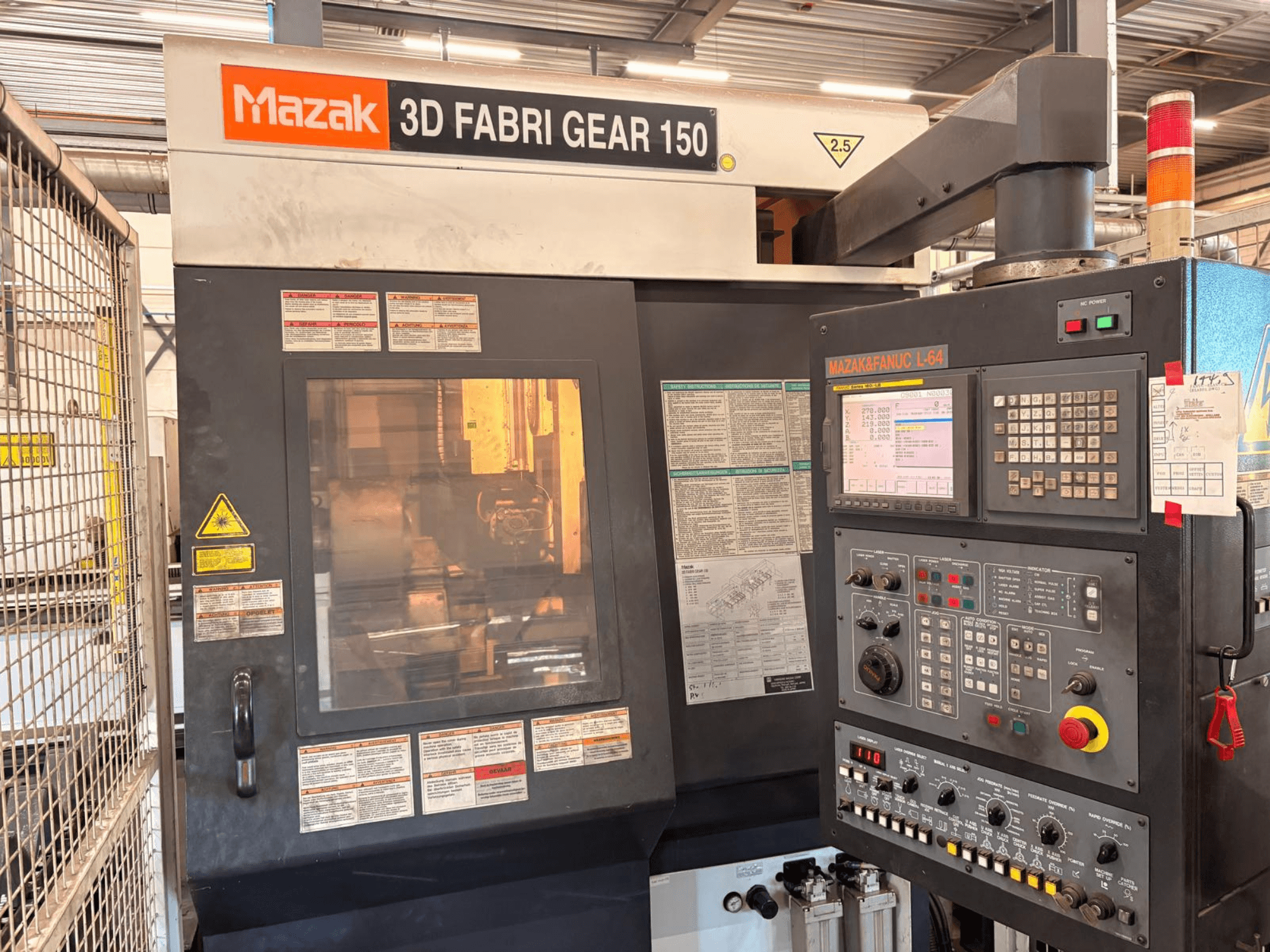 „Mazak 3D Fabri Gear 150“ vamzdžių pjovimo staklės, vaizdas iš priekio, kuriame matomas valdymo skydas, saugos etiketės ir valdymo sąsaja.