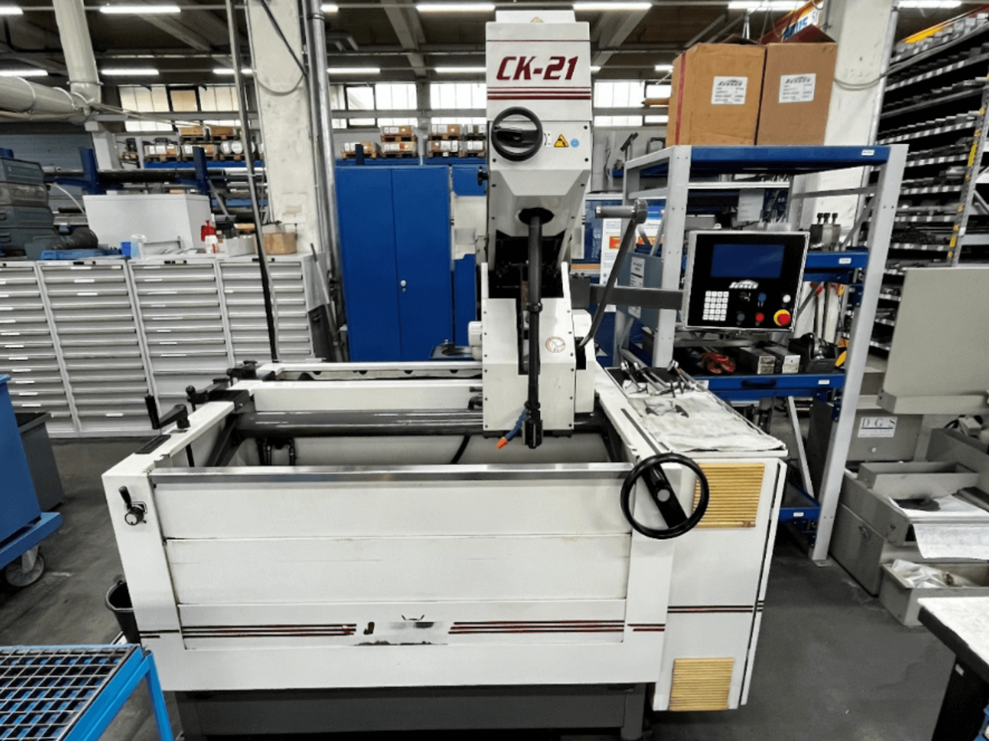 Sunnen CK-21-CC vertikaliojo honavimo staklės iš priekio, fone - valdymo įtaisai, honavimo zona ir pagalbinė įranga.