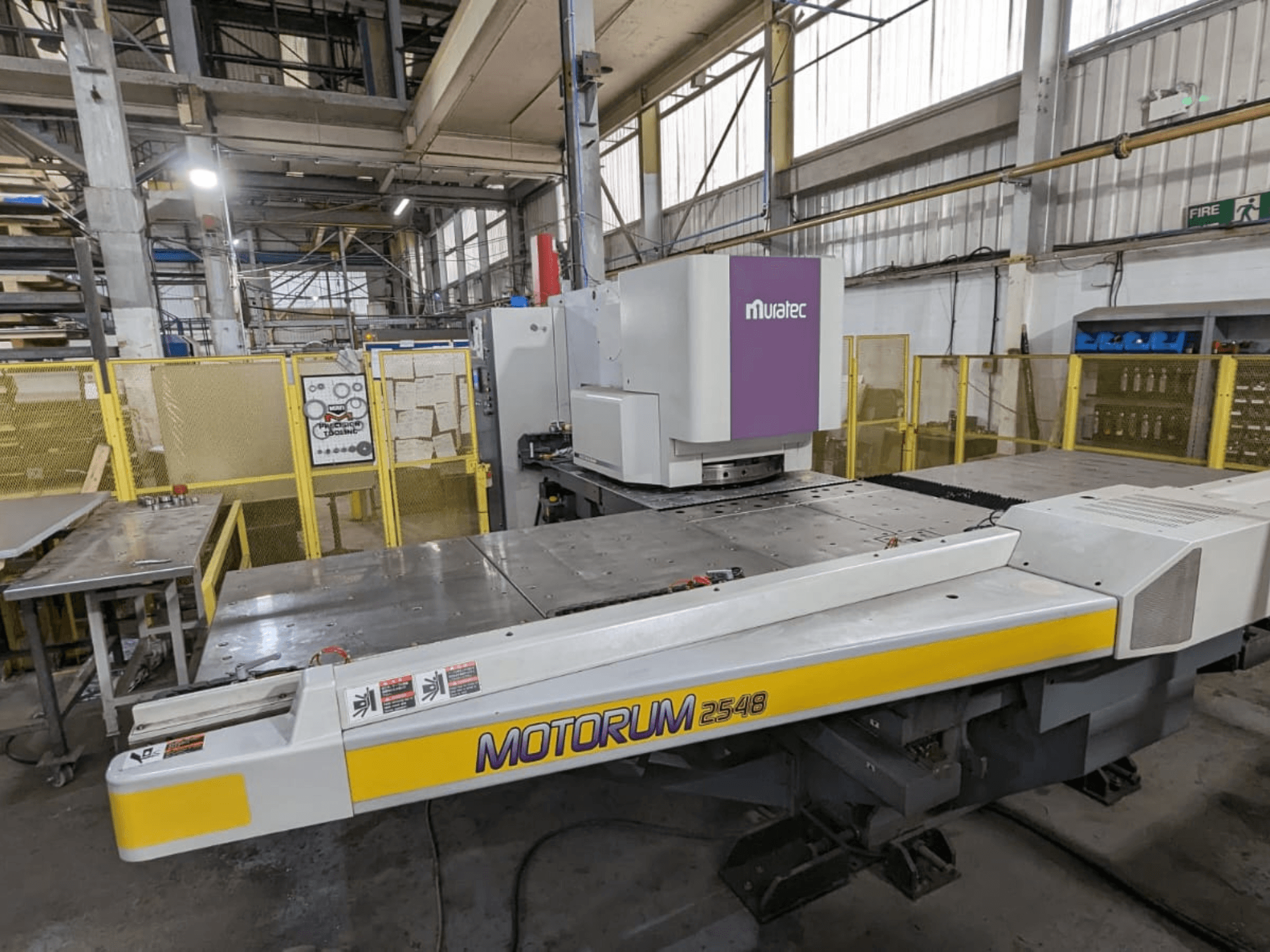 „Muratec MOTORUM 2548“ CNC štampavimo presas, vaizdas iš priekio, kuriame matomas valdymo pultas ir darbo stalas gamyklinėse sąlygose.