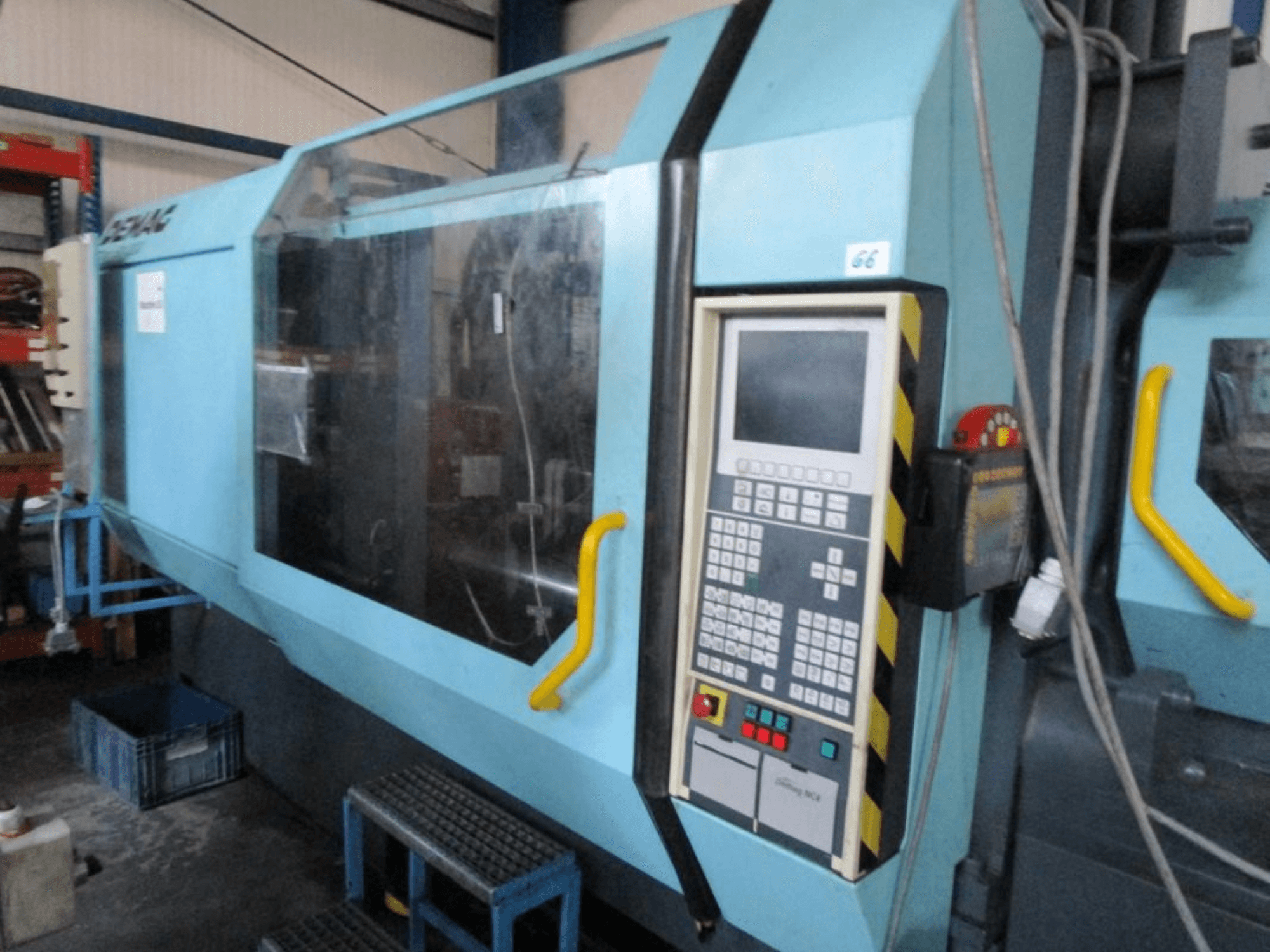 "Demag Erdotech 500-3300" hidraulinė liejimo mašina, vaizdas iš priekio, su valdymo pultu ir skaidriu apsauginiu gaubtu.