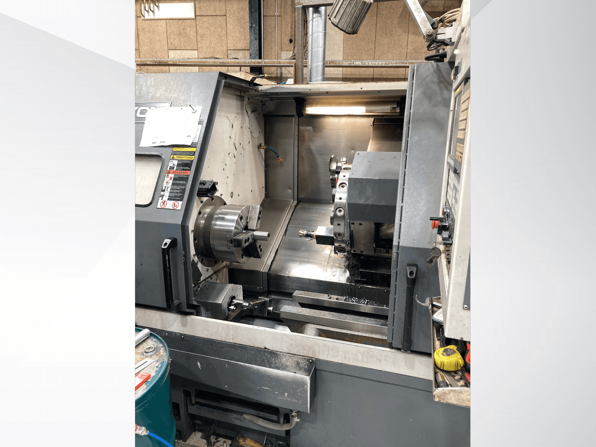 Horizontalios tekinimo staklės YCM GT-300LMB, priekinis vaizdas, kuriame matomas valdymo skydelis ir besisukantis griebtuvas su įrankių sąranka.