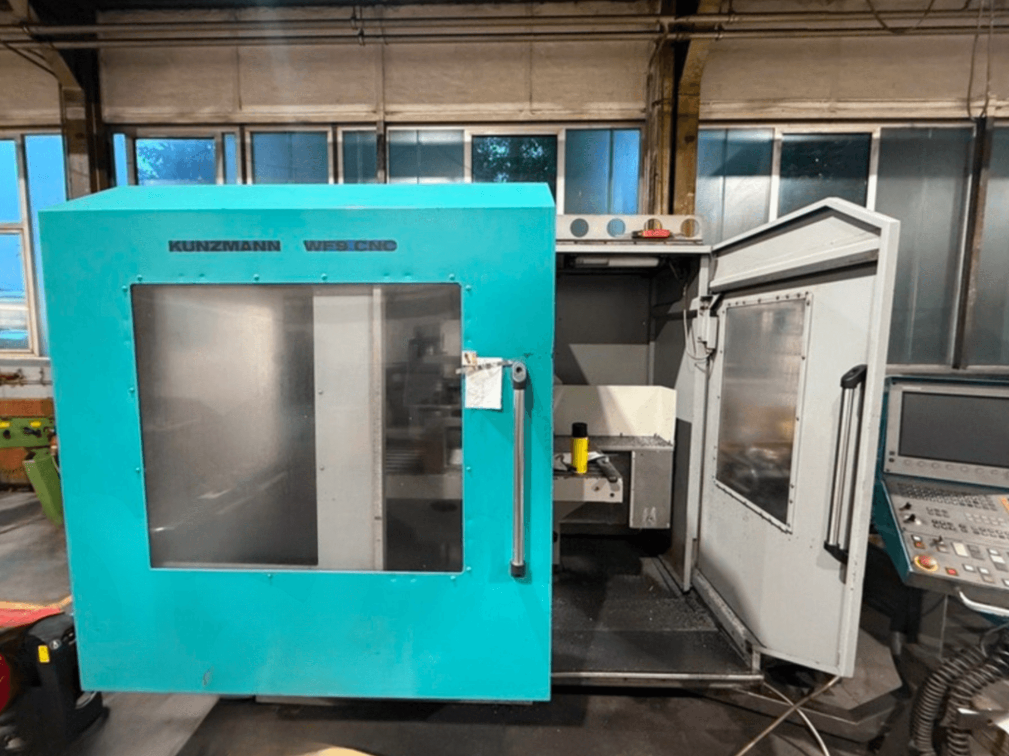 KUNZMANN WF9 CNC vertikalusis apdirbimo centras, vaizdas iš priekio su atidarytomis durimis, matomas vidus ir valdymo skydelis.