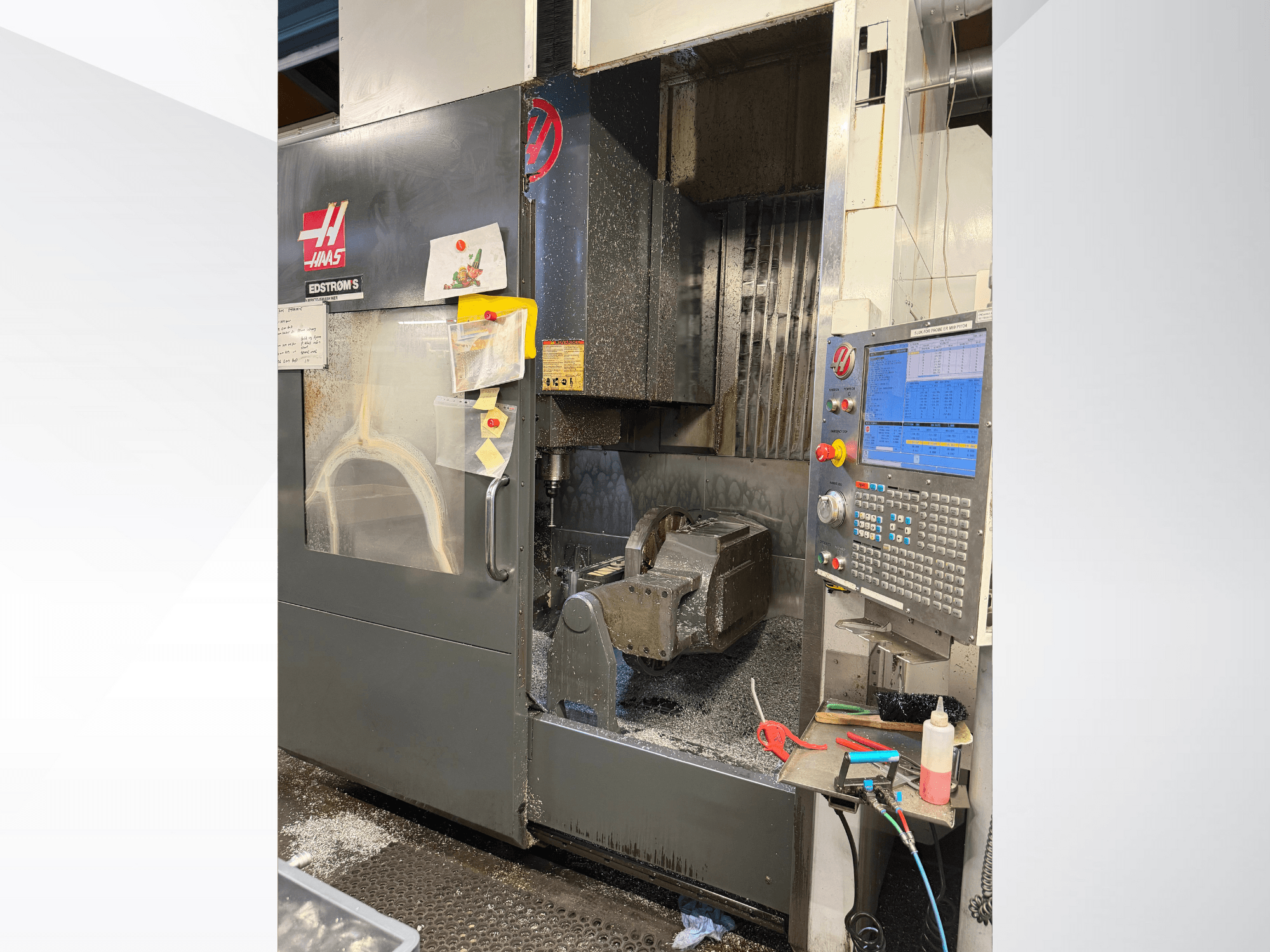 Haas CNC staklių modelis EDSTROM S, priekinis vaizdas, kuriame matomas metalinis ruošinys, valdymo skydelis ir viduje esančios metalo drožlės.