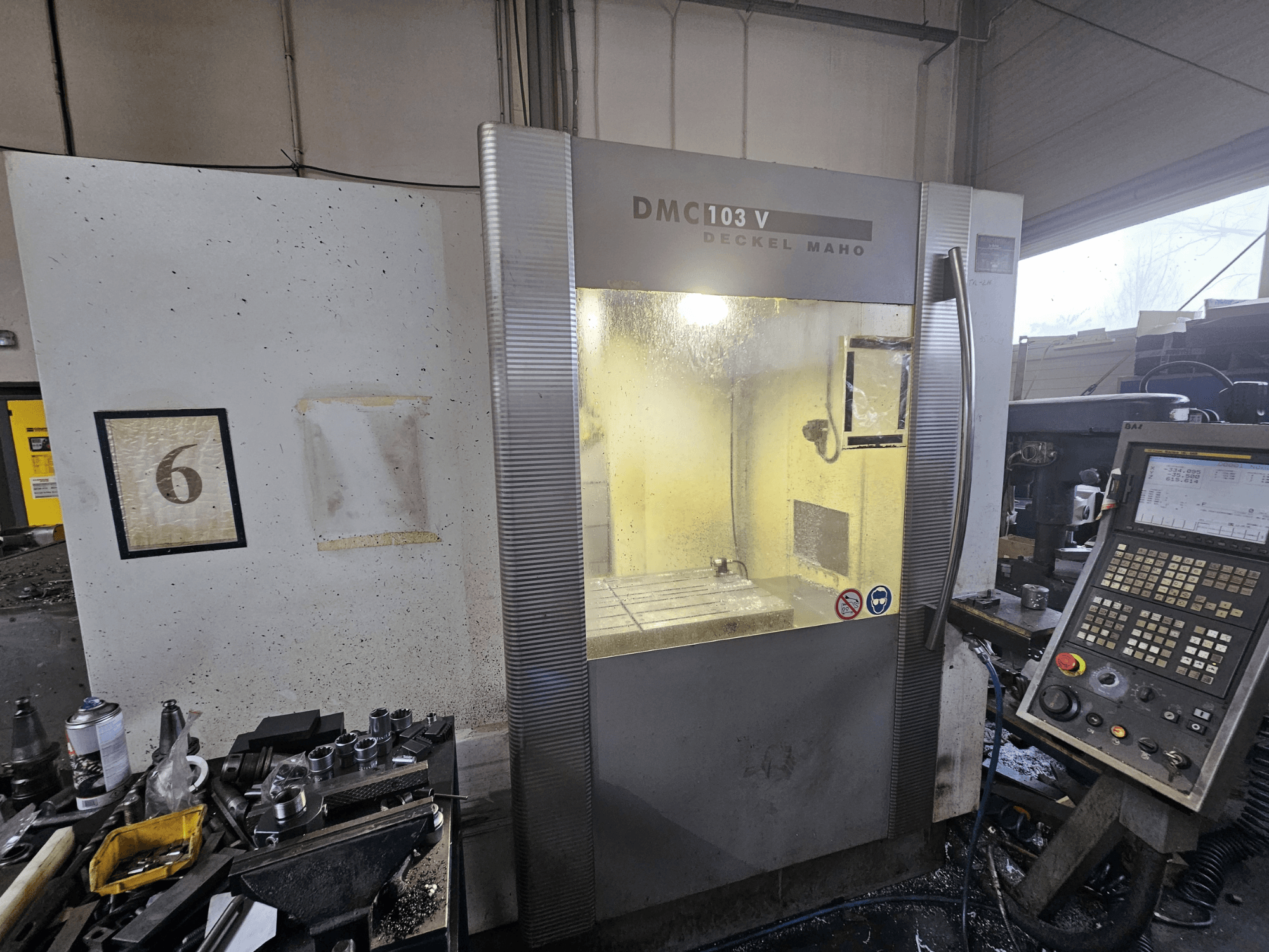 Deckel Maho DMC 103 V CNC staklių priekinis vaizdas, kuriame matyti valdymo skydelis, darbo zona ir numeruotas indikatorius "6".