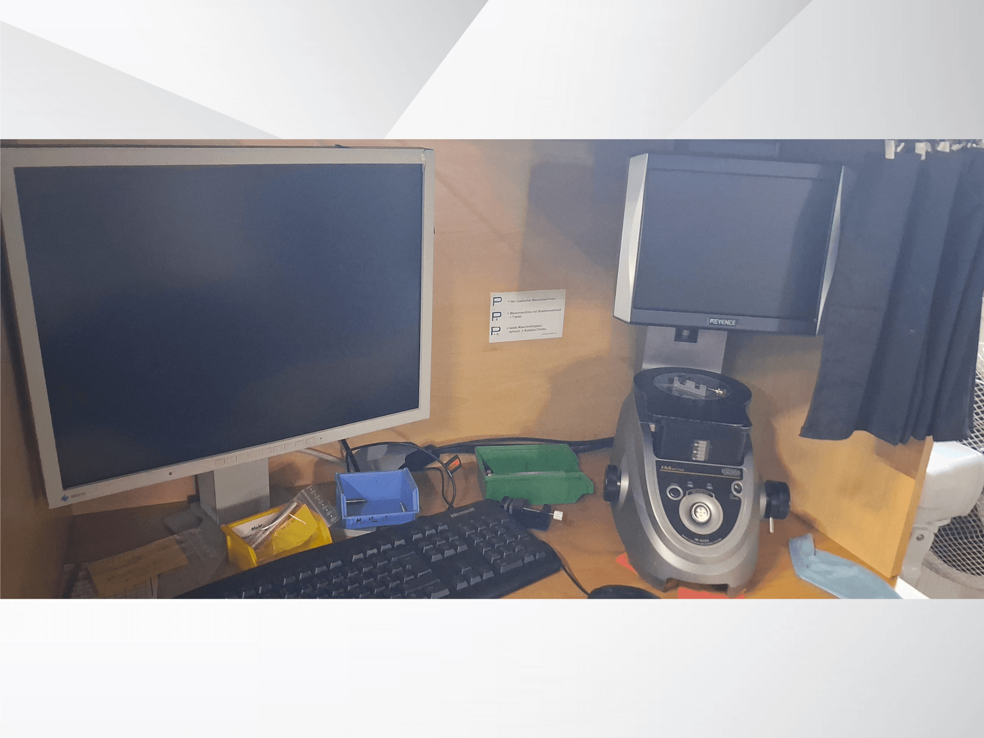 Kompiuterio monitorius su klaviatūra, PEVA prekės ženklo ekranas ir pilkas laboratorinis prietaisas ant medinio stalo su įvairiais dėklais ir popieriais.