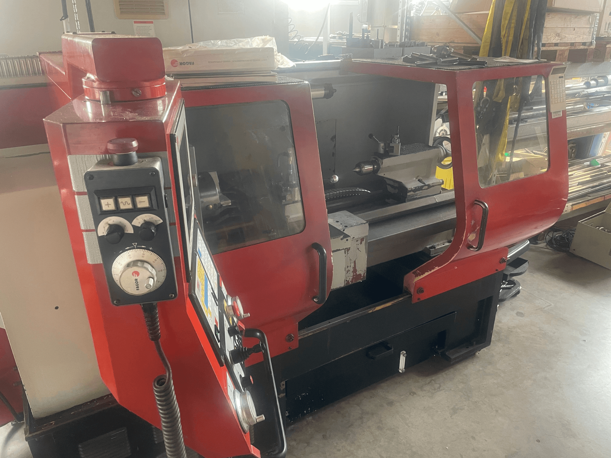 EMCO EMCOMAT 200X1000 horizontalusis tekinimo staklės, vaizdas iš šono, kuriame matomi valdymo elementai, stiklinis gaubtas ir tekinimo staklių konfigūracija.