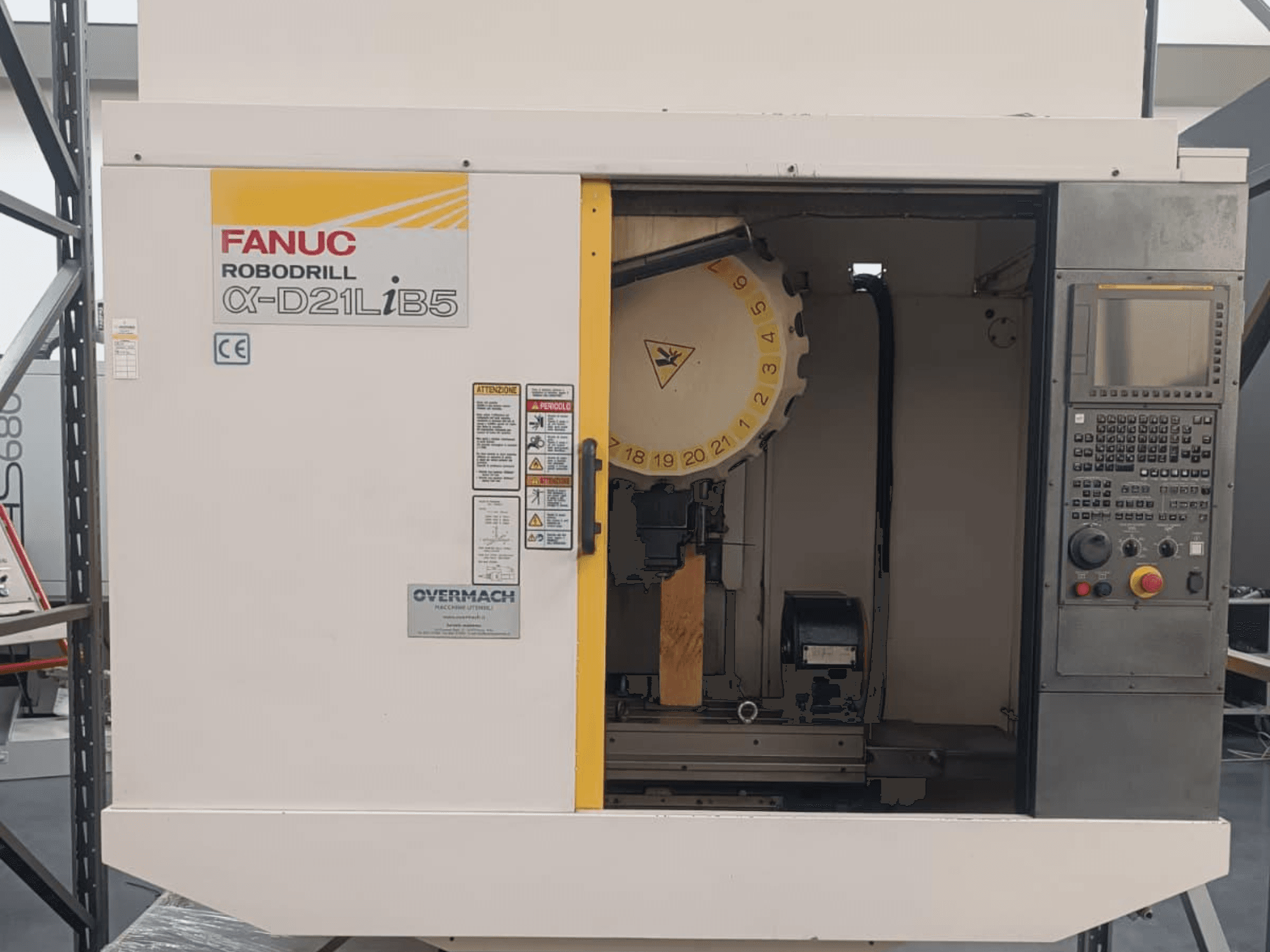 FANUC Robodrill α-D21LiB5, vaizdas iš priekio; CNC staklės su matomu įrankių laikikliu, valdymo skydeliu ir saugos įspėjimais.