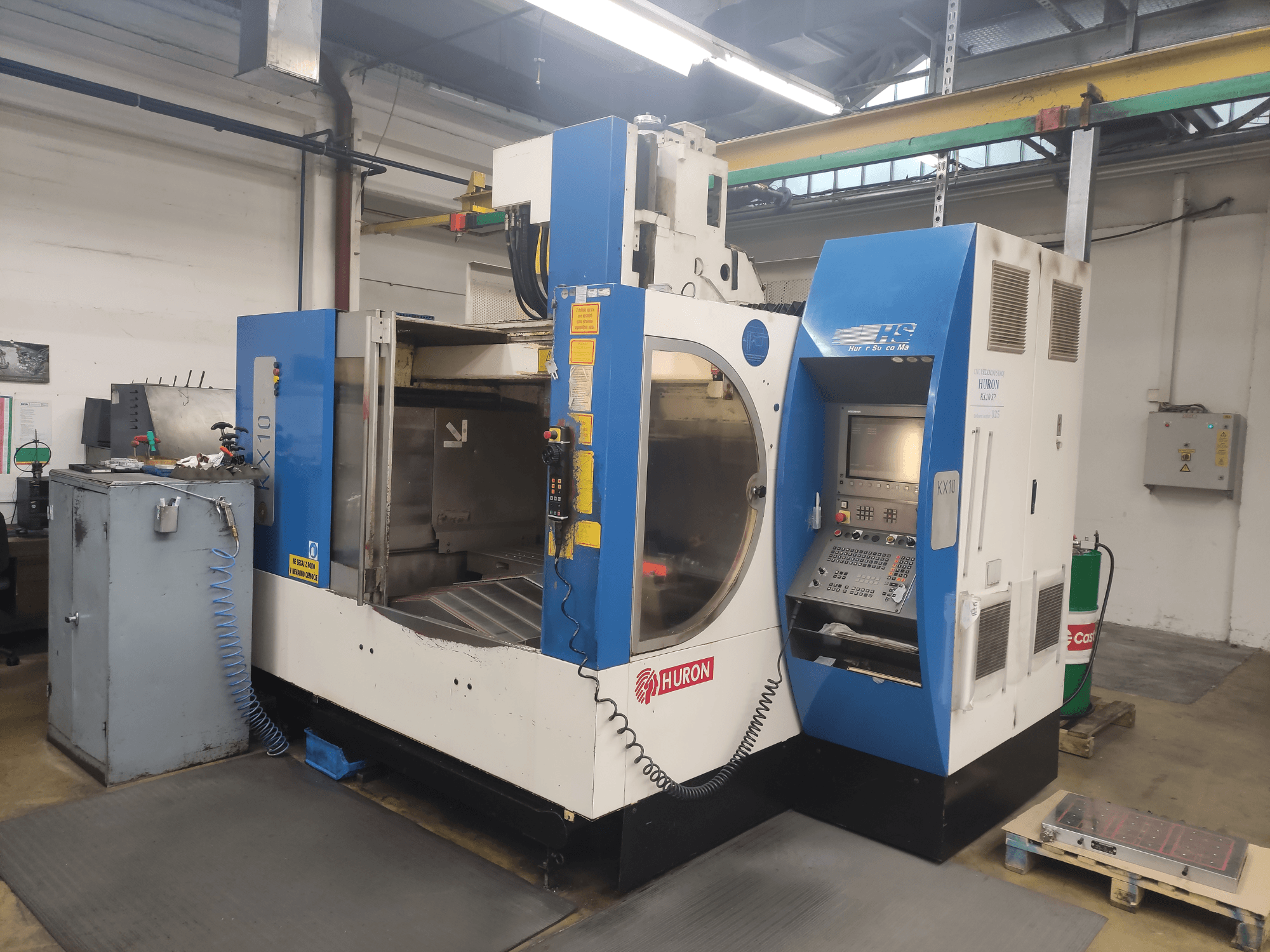 HURON KX10 CNC staklės dirbtuvėse, vaizdas iš priekio, su valdymo pultu ir didele apdirbimo anga.