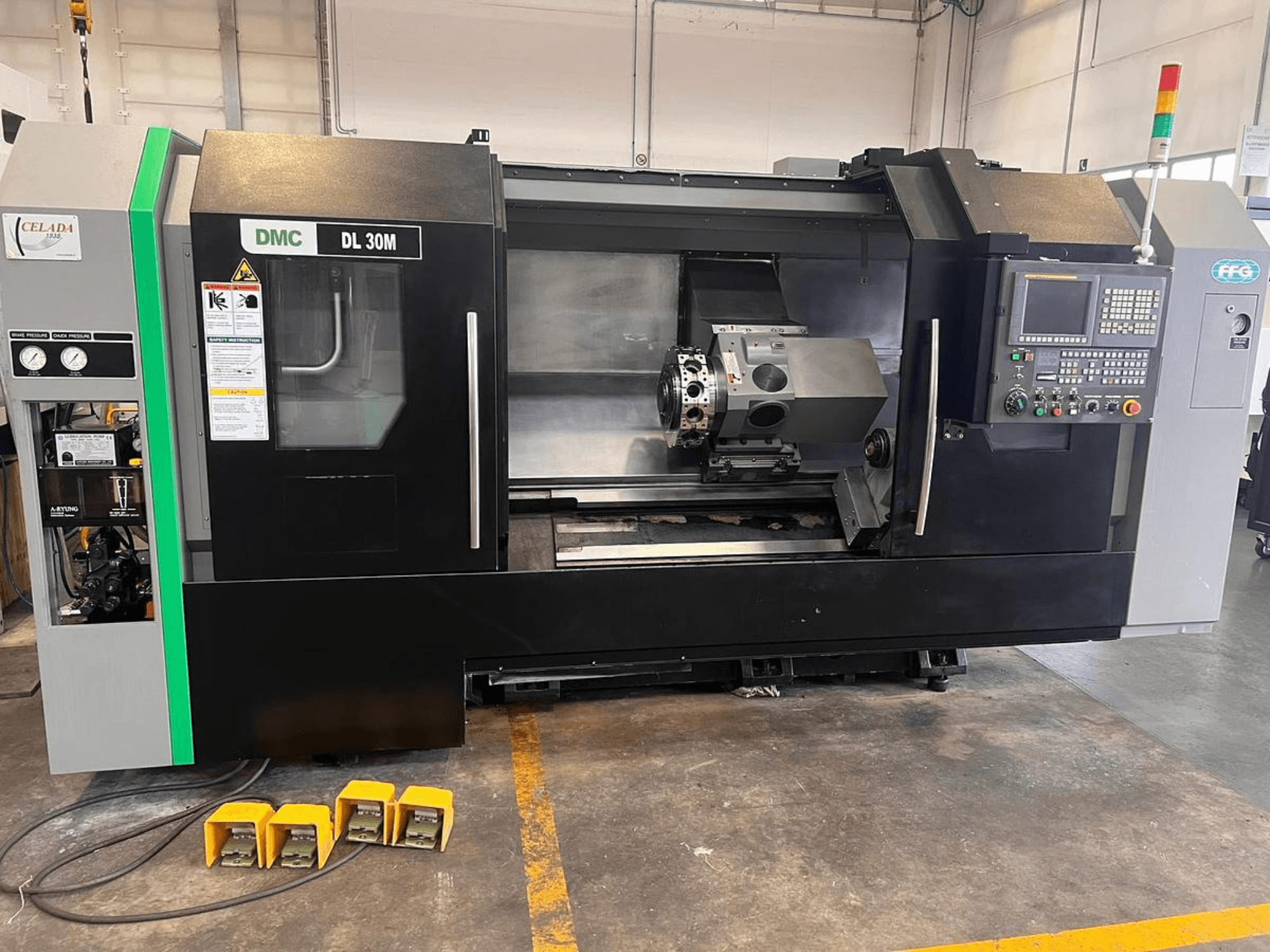 DMC DL 30M CNC staklės su šoniniu vaizdu, kuriame matomi valdikliai, suklys ir trys pedalai ant grindų.