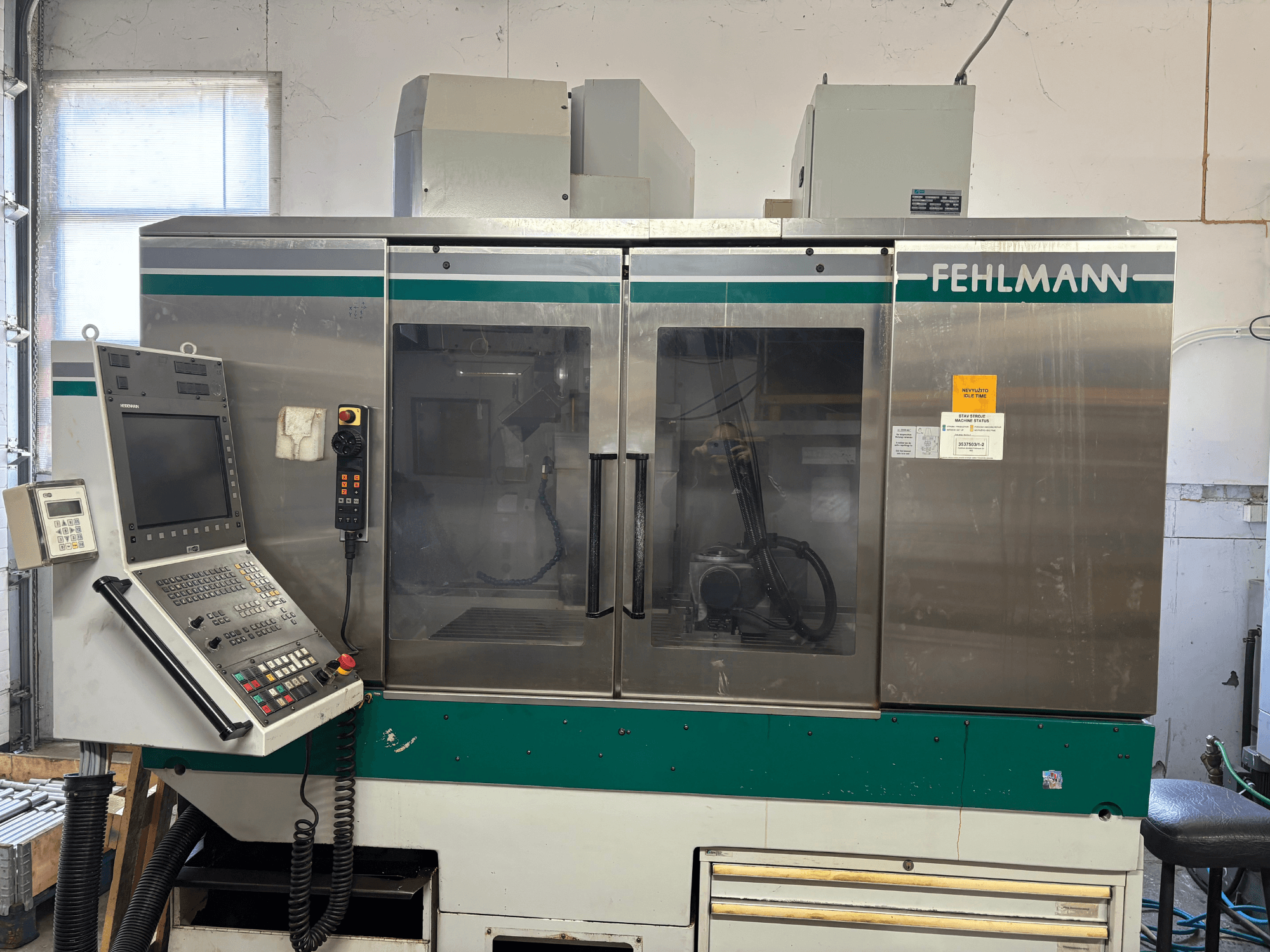 FEHLMANN Picomax 90-M vertikaliojo apdirbimo centro vaizdas iš priekio, kuriame matomas valdymo skydas, skaidrus gaubtas ir valdymo mygtukai.