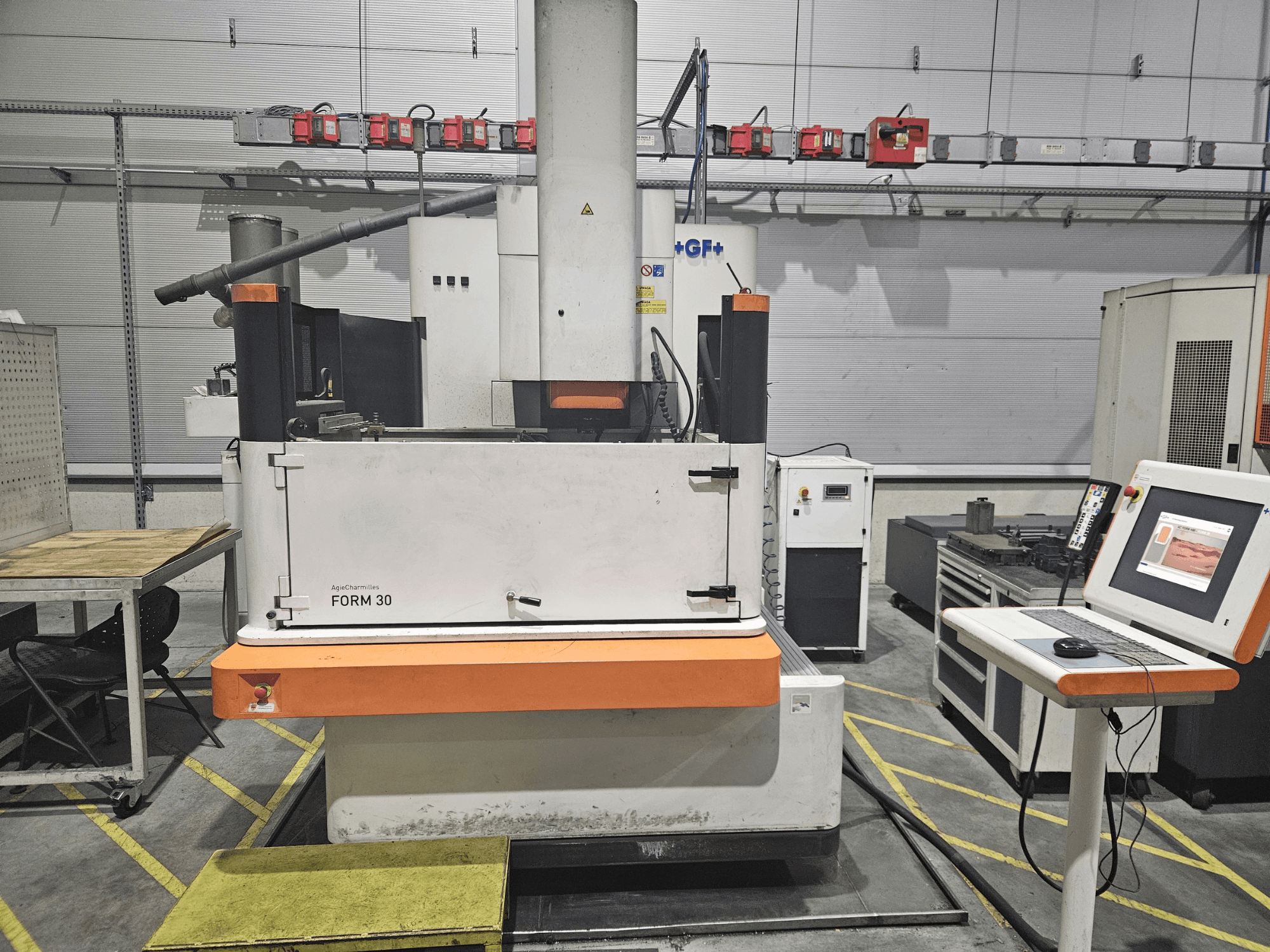 "ApeqChemicals FORM 30" mašina dirbtuvėse, vaizdas iš priekio su valdymo pultu ir darbo stalu šone.