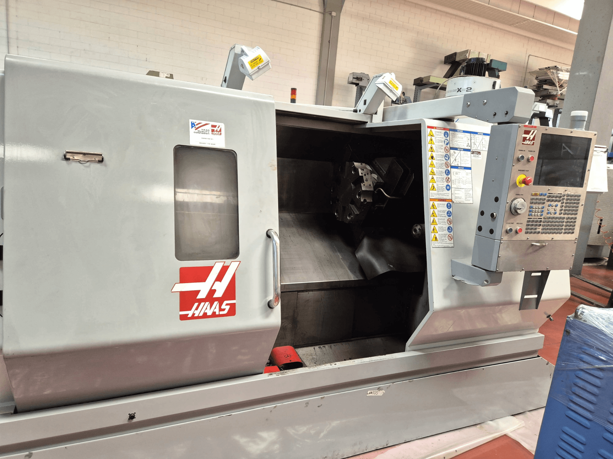 Haas SL 30TBHE horizontalus tekinimo staklės, vaizdas iš priekio, kuriame matomi valdymo elementai ir atviras skyrius, skirtas apdirbimo operacijoms.