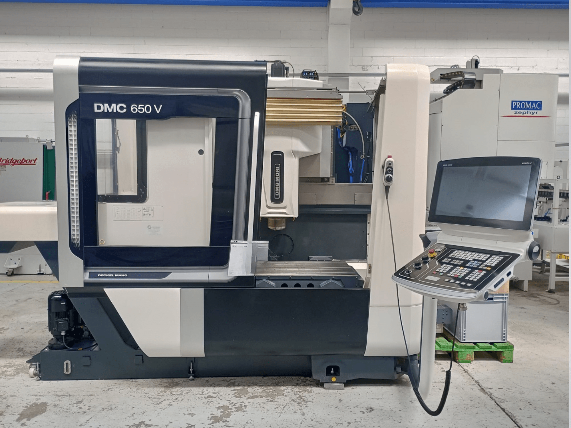 Decker Maho DMC 650 V CNC staklių vaizdas iš šono, valdymo skydelis su mygtukais ir ekranu, pramoninėje aplinkoje.