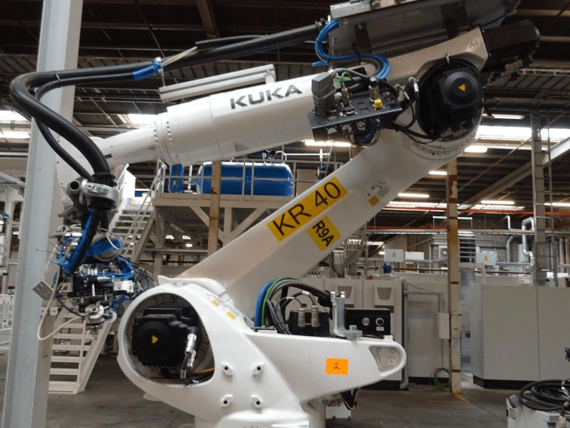 KUKA KR 120 R3100-2 roboto rankos šoninis vaizdas, valdymo skydelis ir mechaniniai komponentai pramoninėje aplinkoje.