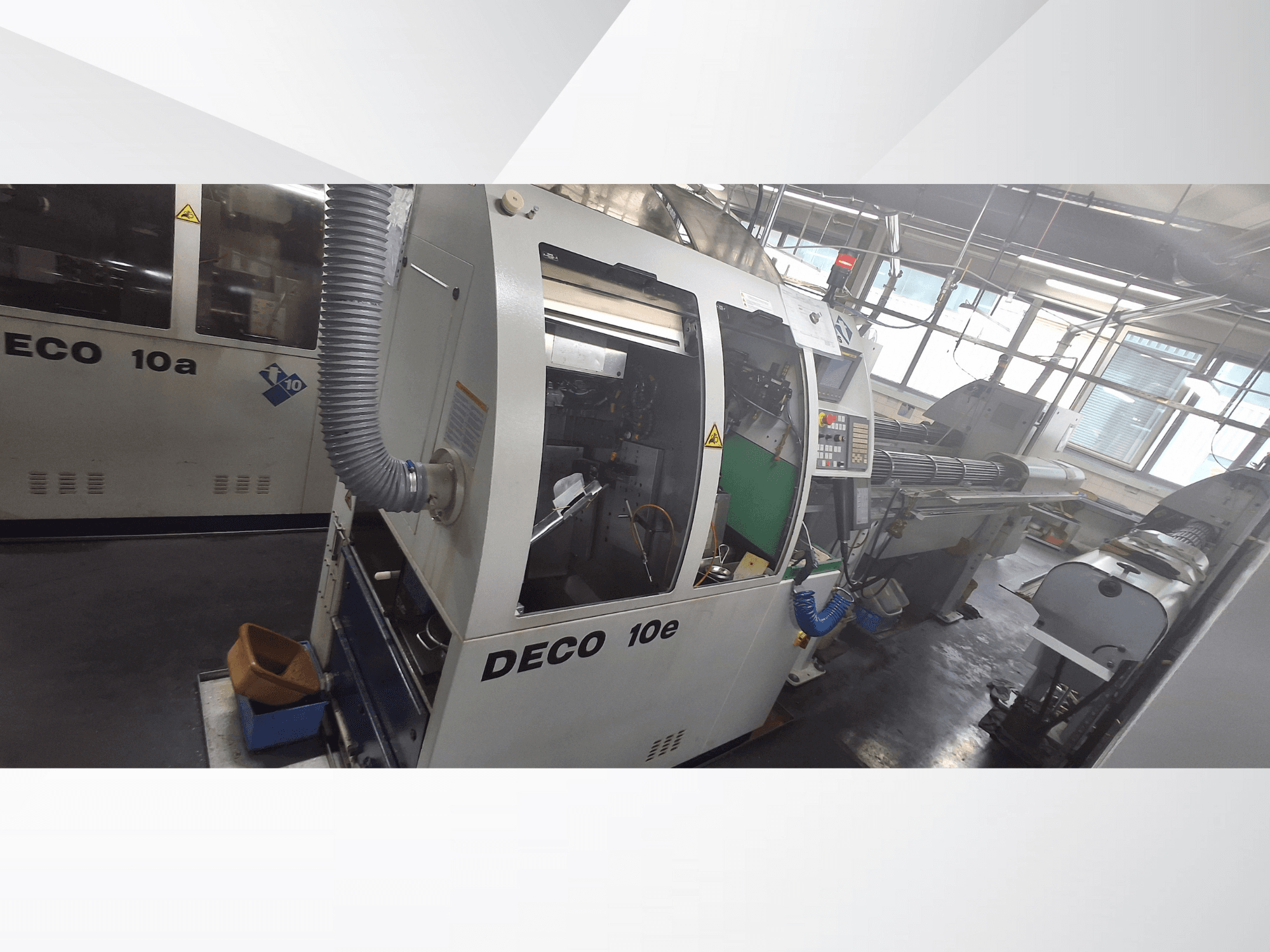DECO 10e CNC staklės iš šono, su valdymo skydeliu, žaliu vidumi ir prijungta išmetimo žarna.