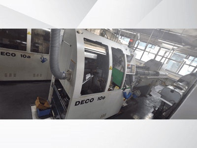 DECO 10e CNC staklės iš šono, su valdymo skydeliu, žaliu vidumi ir prijungta išmetimo žarna.