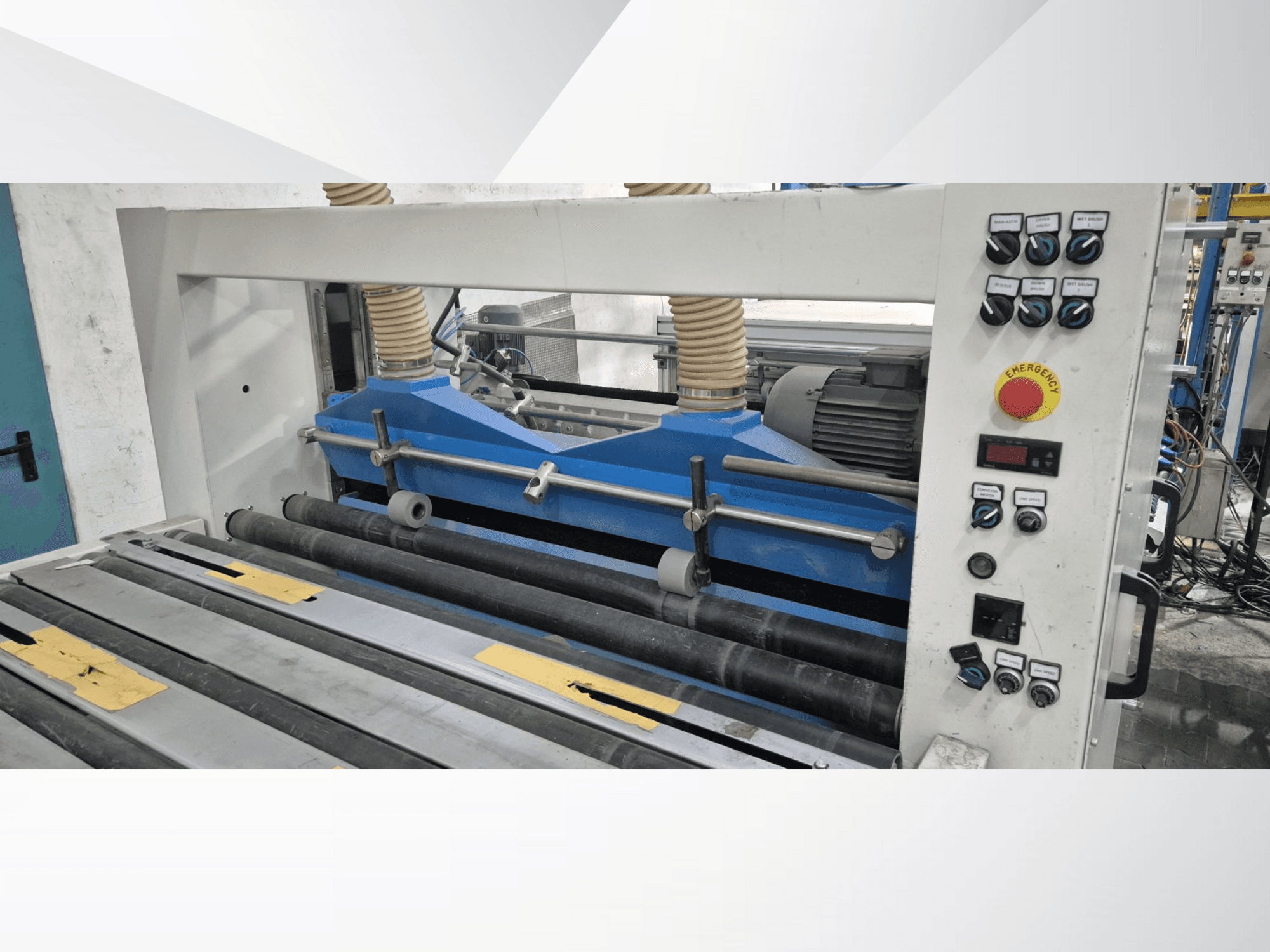 Pramoninė valcavimo mašina su mėlynais komponentais, vaizdas iš priekio, su valdymo skydeliu ir avarinio stabdymo mygtuku.