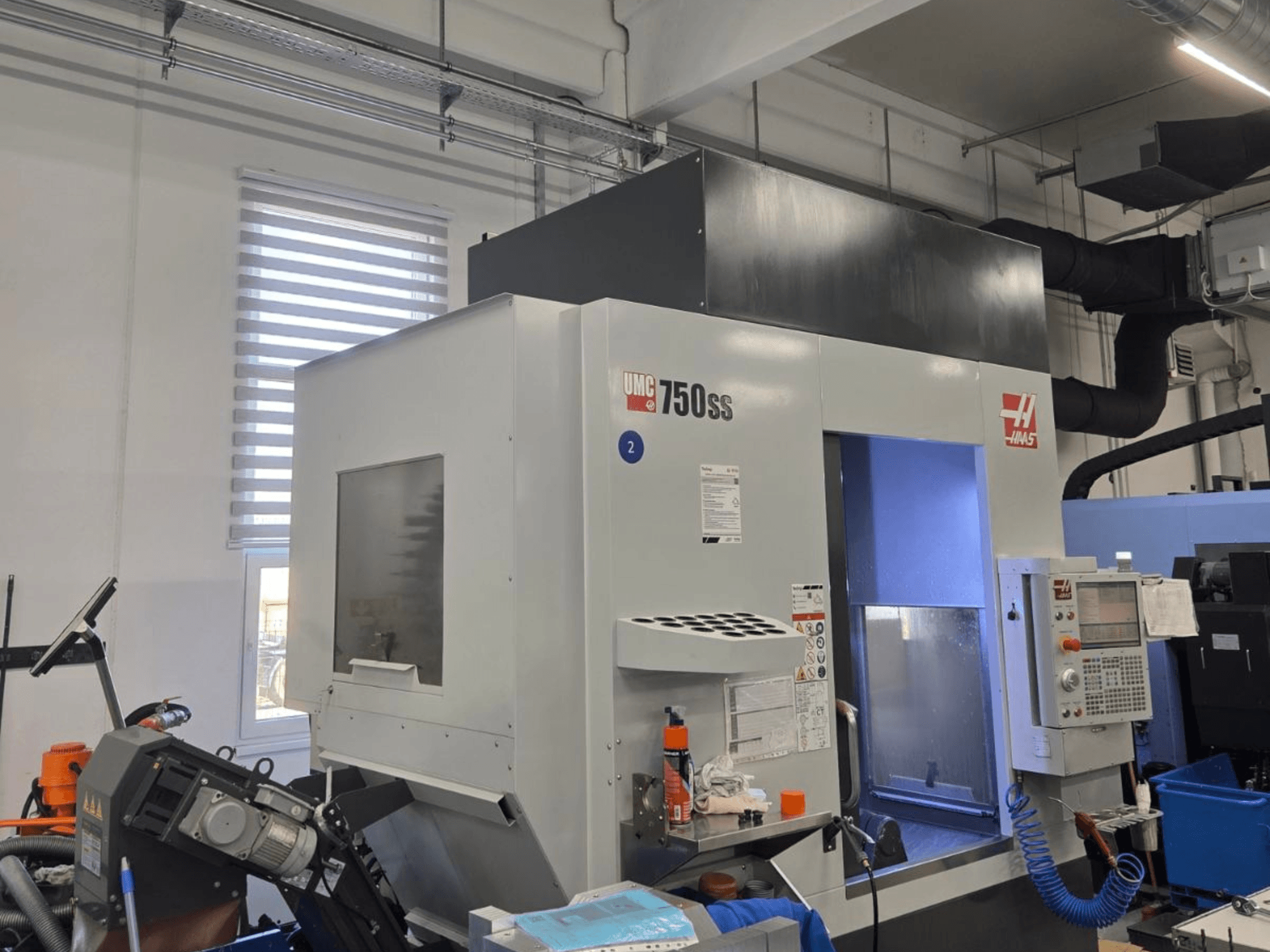 Vertikalusis apdirbimo centras "Haas UMC-750SS", vaizdas iš priekio, su valdymo skydeliu ir laisva prieiga prie apdirbimo zonos.