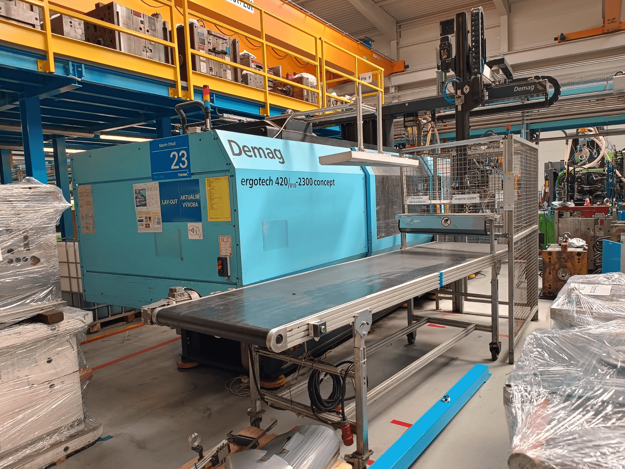 Demag ergotech 420/810 - 2300 hidraulinės įpurškimo liejimo mašinos su konvejeriu ir apsauginiu gaubtu iš šono.