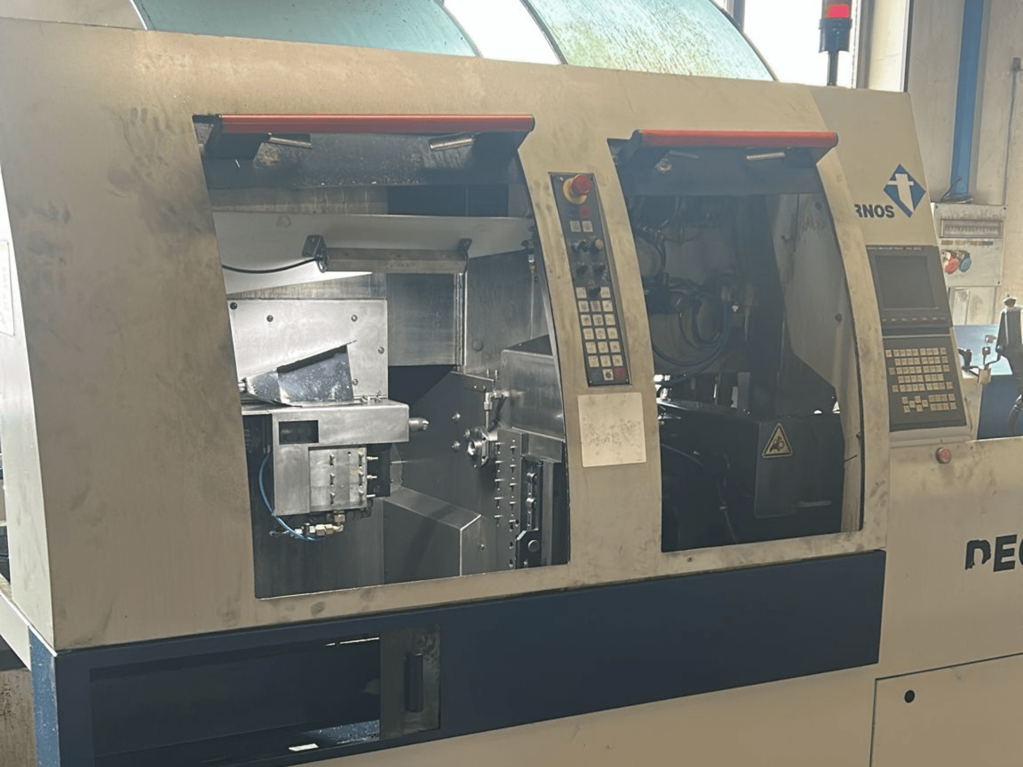 Alt tekstas: Deco 13 b šveicariško tipo tekinimo staklių TORNOS Deco 13 b vaizdas iš priekio su matomais valdymo skydais ir vidiniais komponentais.