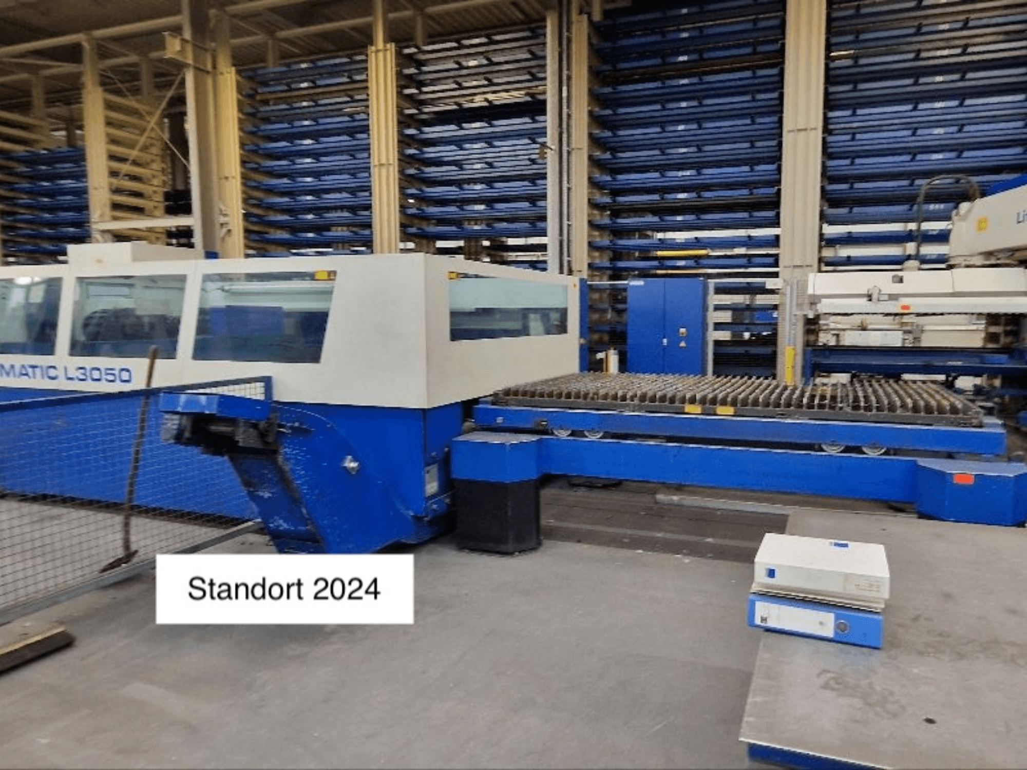 TRUMPF Trumatic L3050 CO2 lazerinio pjovimo staklės iš priekio, su didele pjovimo lova ir valdymo pultu.