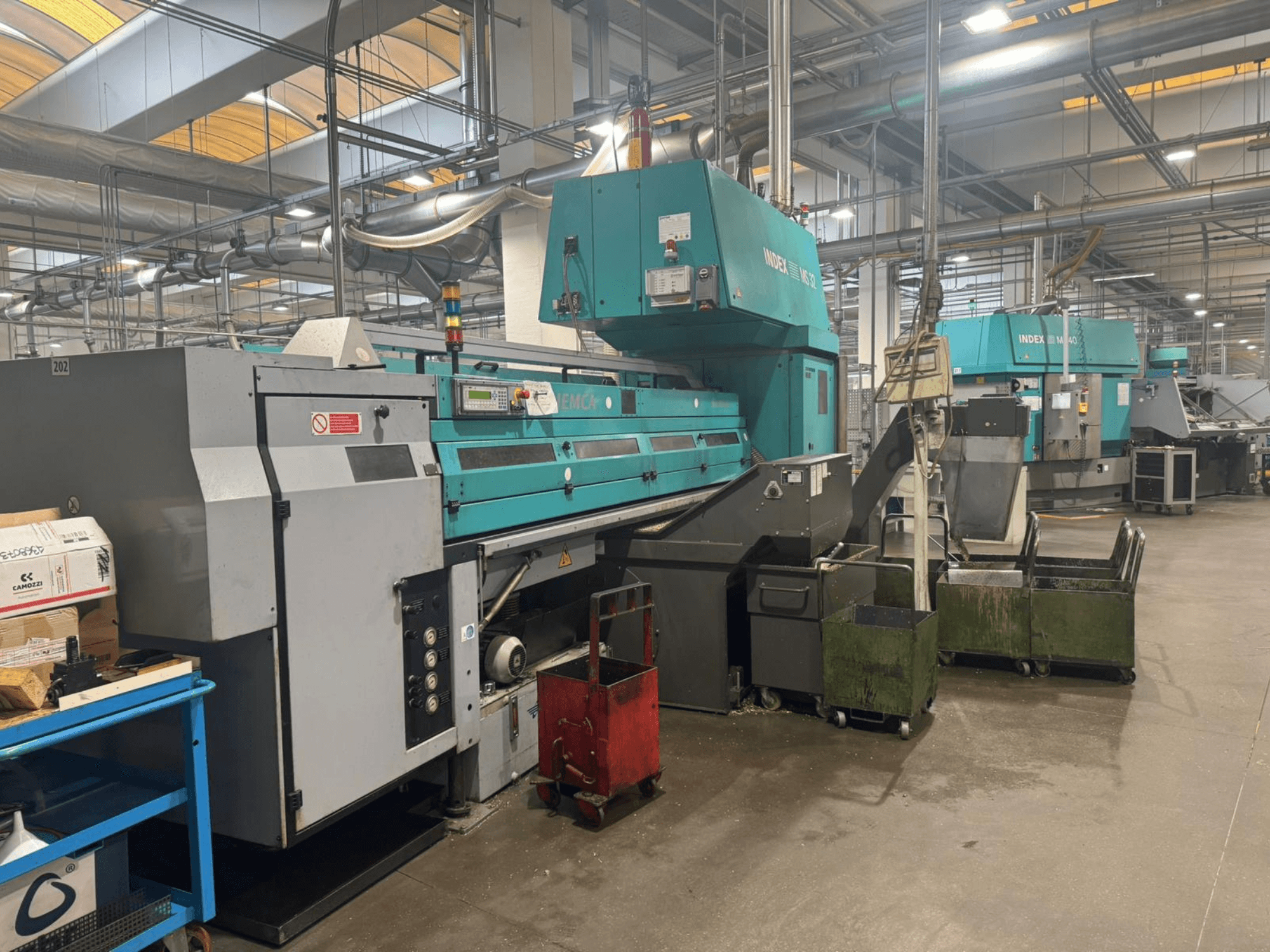 Daugiasvirtės tekinimo staklės INDEX MS32C, priekinis vaizdas, kuriame matomi valdymo elementai ir darbinė zona dirbtuvėse.