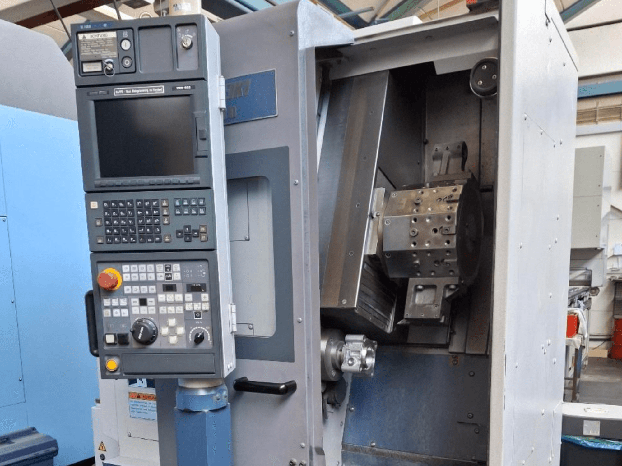 MORI SEIKI SL 1000 horizontaliųjų tekinimo staklių priekinis vaizdas su valdymo skydeliu ir išsamiu vidiniu mechanizmu.