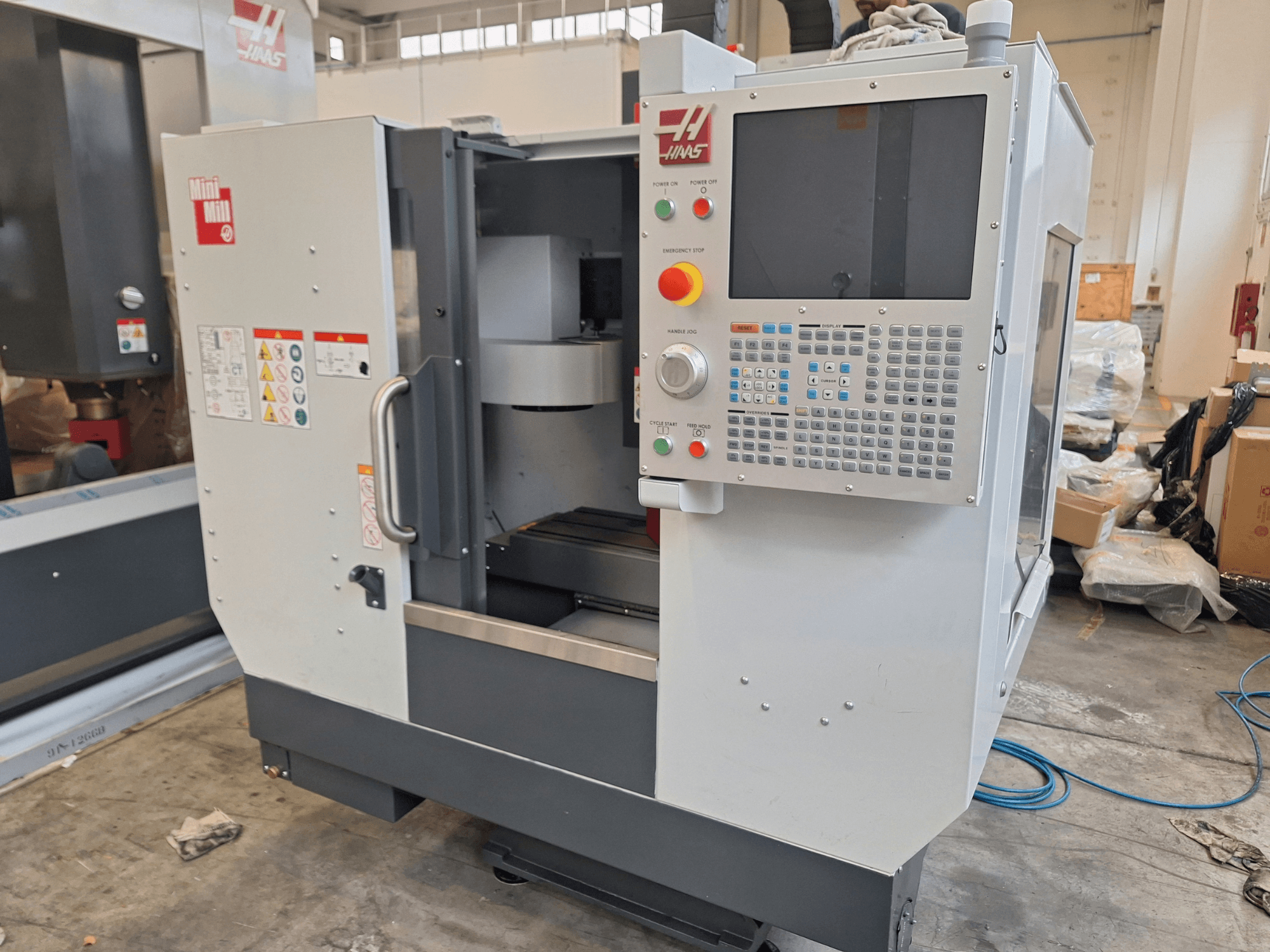 Vertikalusis apdirbimo centras „HAAS Mini Mill“, vaizdas iš priekio, kuriame matomas valdymo skydelis su mygtukais ir ekranu.