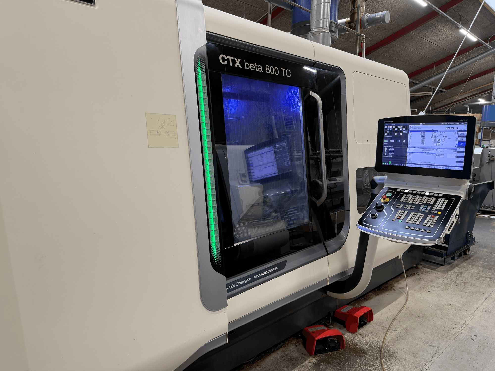 CTX beta 800 TC CNC staklės iš šono, su skaitmeniniu valdymo skydeliu ir šviečiančiu žaliu saugos indikatoriumi.