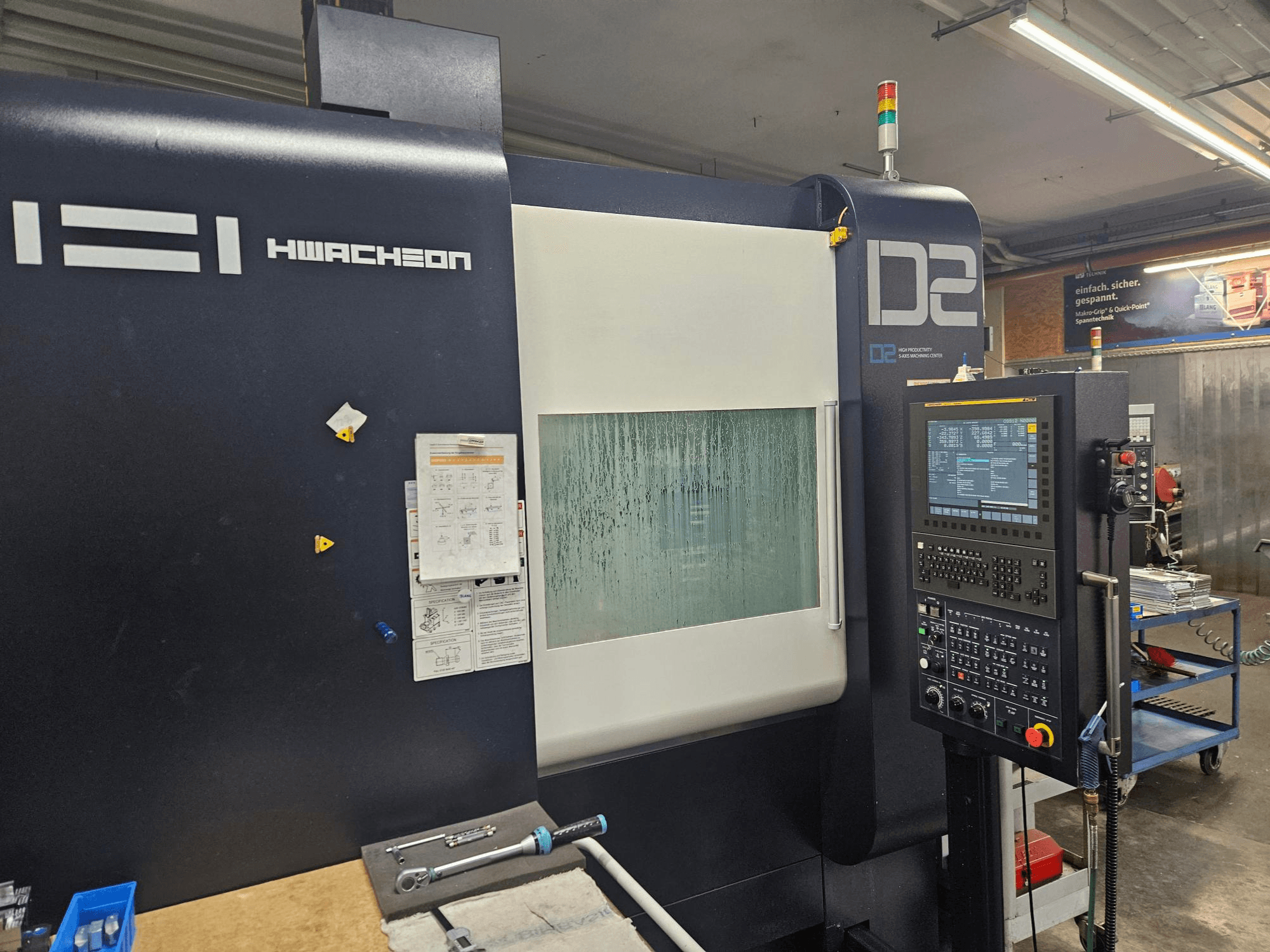 HWACHEON D2-5AX 12k vertikalus apdirbimo centras, vaizdas iš priekio, kuriame matomas valdymo skydas ir apgaruotas stebėjimo langelis.