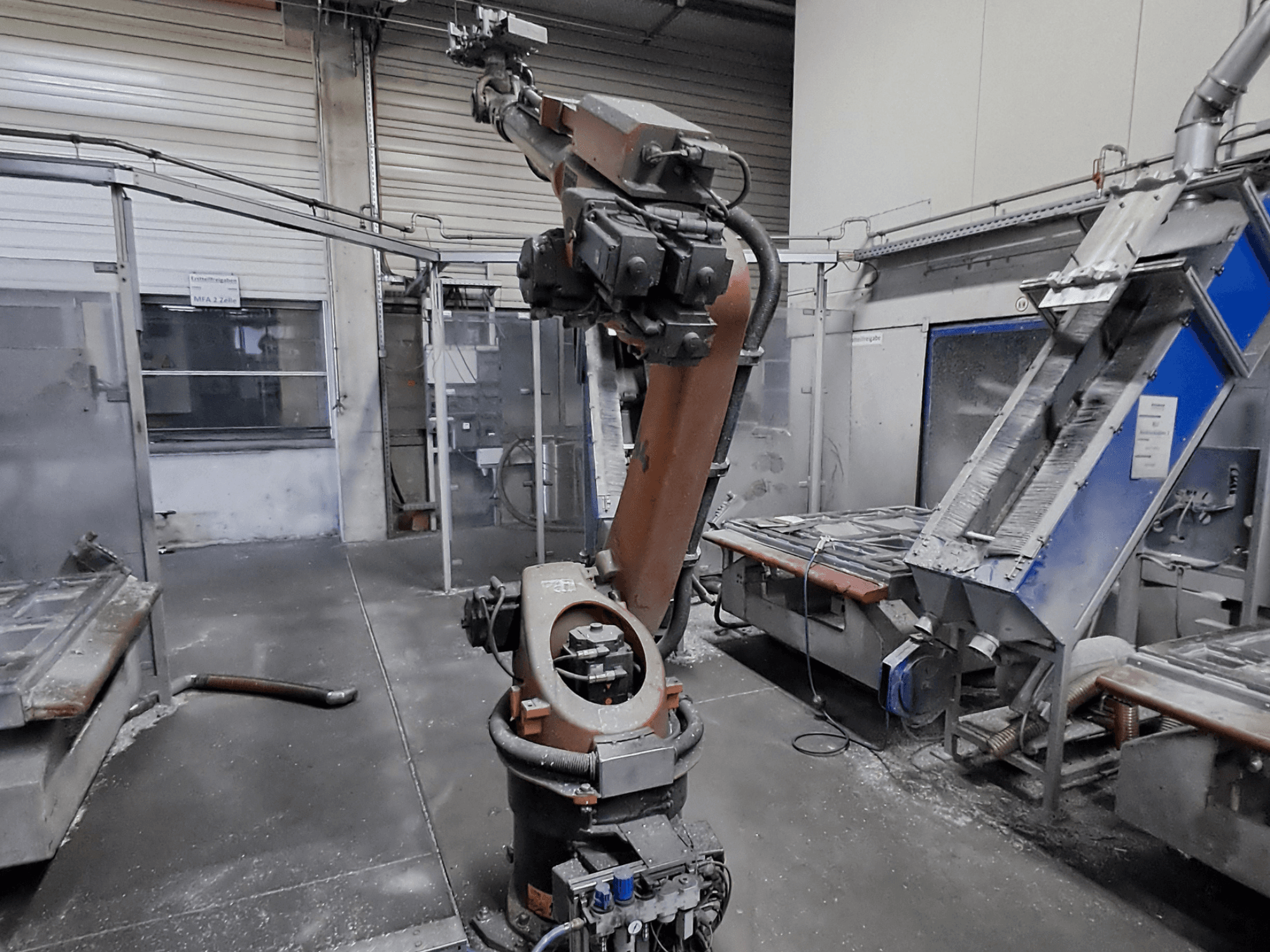 „KUKA KR 30L16-2“ roboto ranka dirbtuvėse, vaizdas iš priekio, fone matosi dulkės ir mašinos.