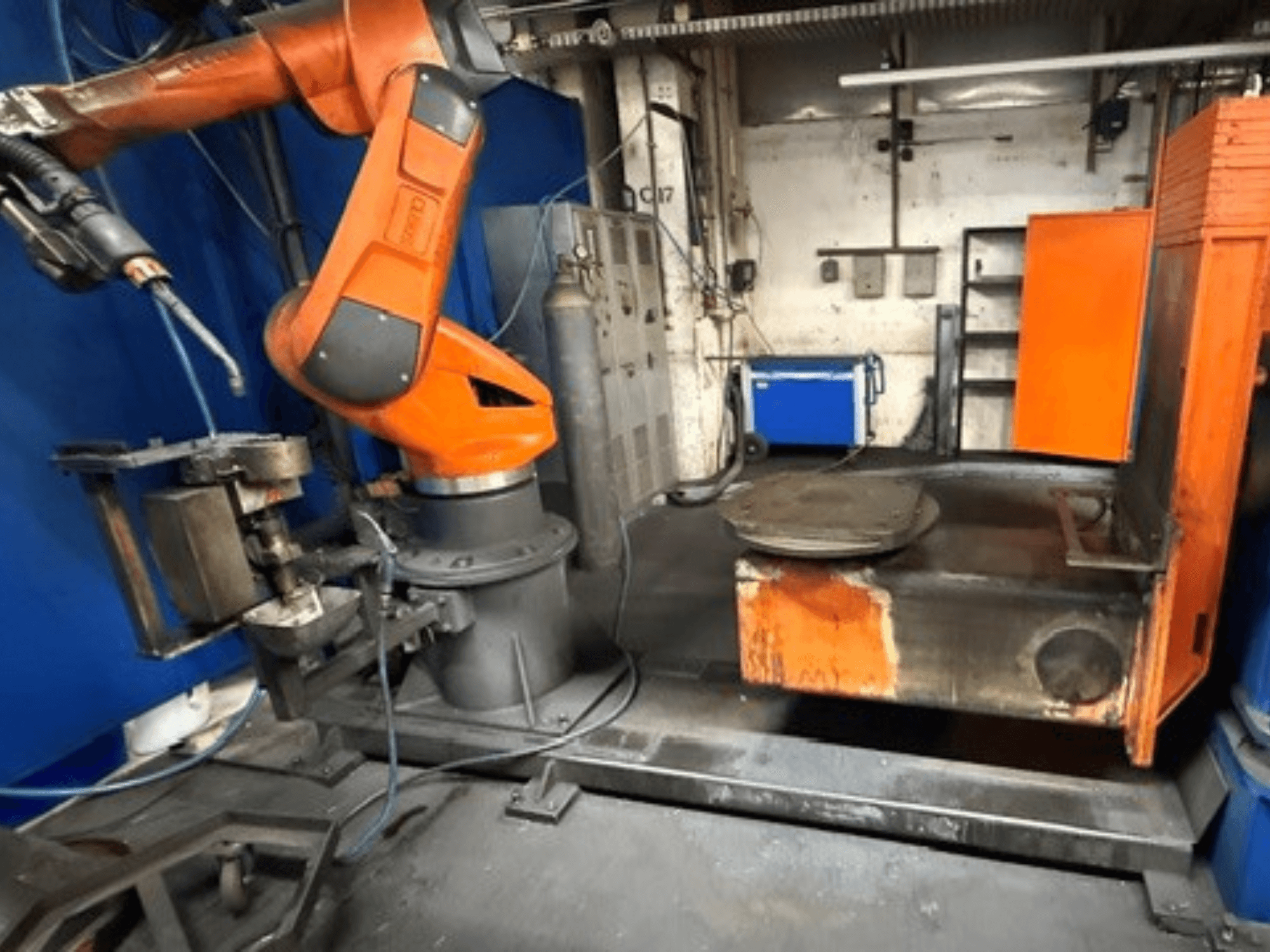 CLOOS C50 suvirinimo robotas, vaizdas iš priekio, su oranžine robotine ranka ir metaliniu darbo stalu.