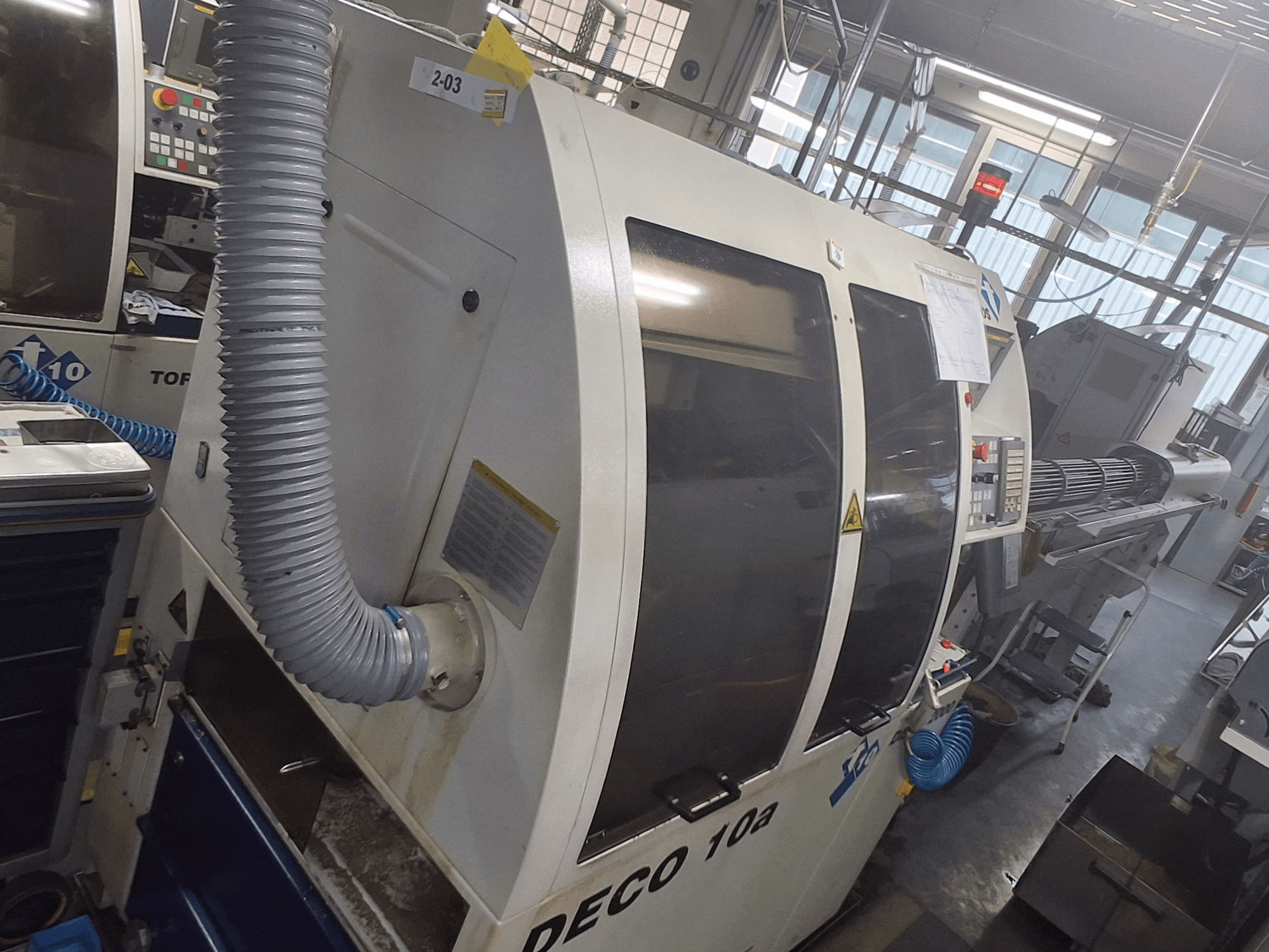 DECO 10a mašinos priekinis vaizdas; matomas didelis valdymo skydelis, ortakiai ir darbiniai lipdukai.