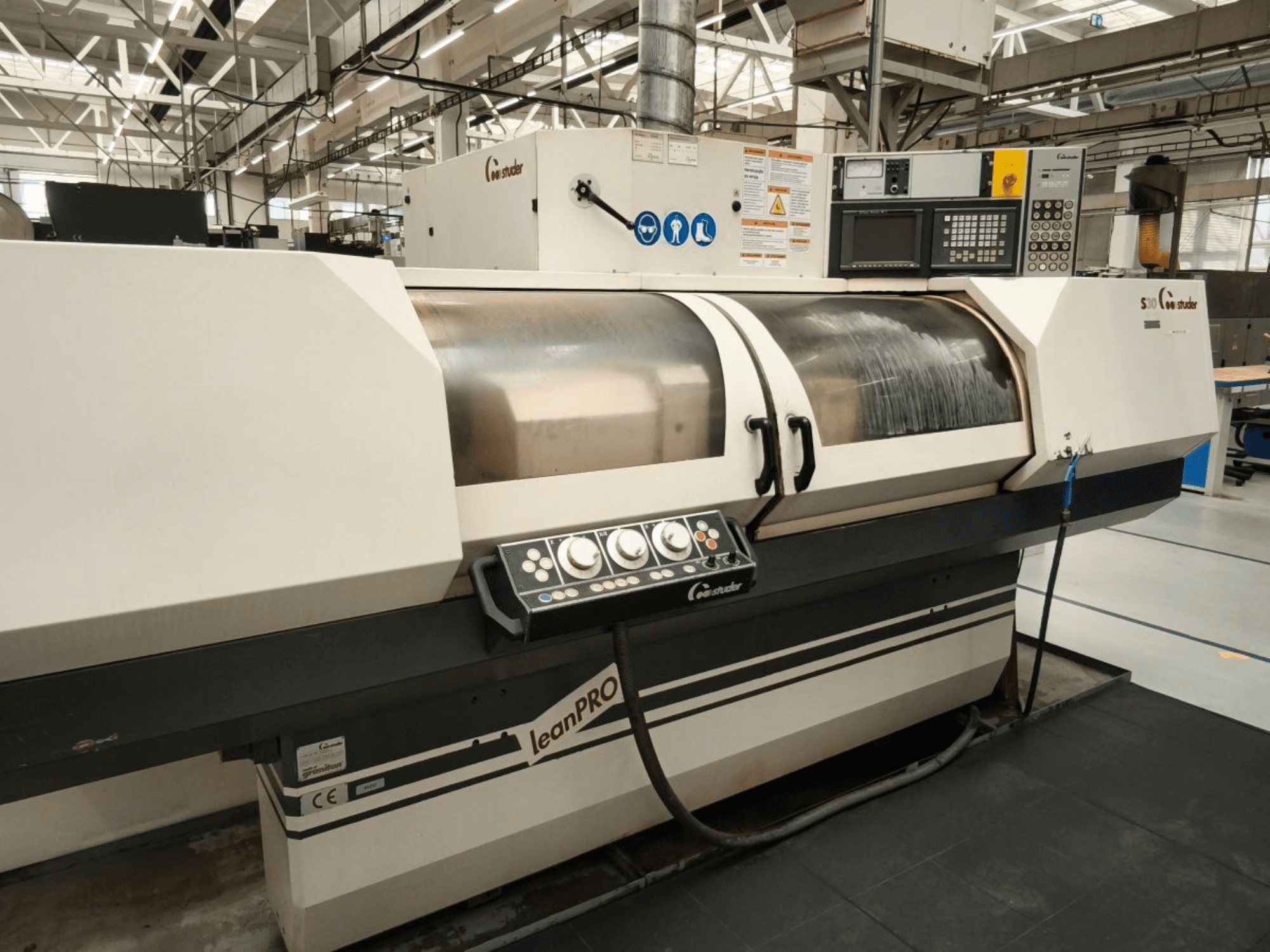 Cilindrinio šlifavimo staklės STUDER S30 LEAN PRO, šoninis vaizdas, kuriame matomas valdymo skydelis ir šlifavimo disko dangtis pramoninėje aplinkoje.