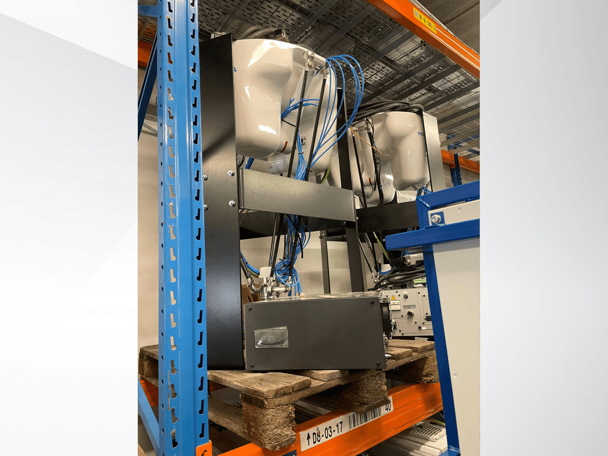 „Yaskawa Motoman MPP3H“ robotas, vaizduojamas iš šono, su matomais laidais ir komponentais ant laikymo stovo.