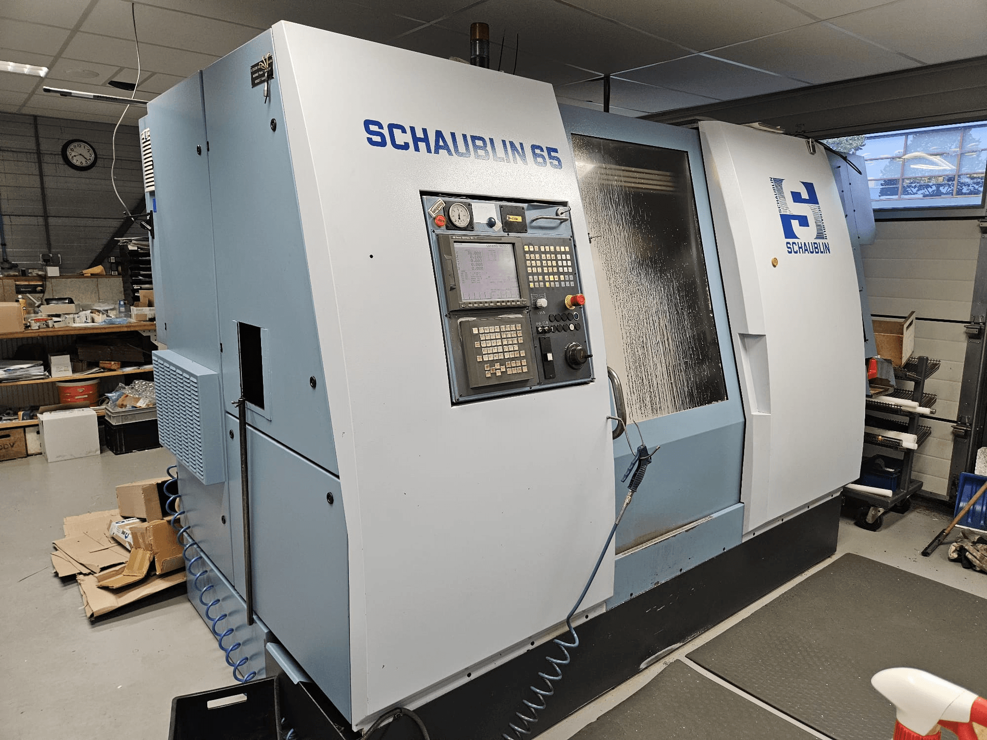 SCHAUBLIN 65 CNC staklės, vaizdas iš šono, valdymo skydelis, mėlynos ir pilkos spalvos korpusas ir matoma aušinimo skysčio sistema.