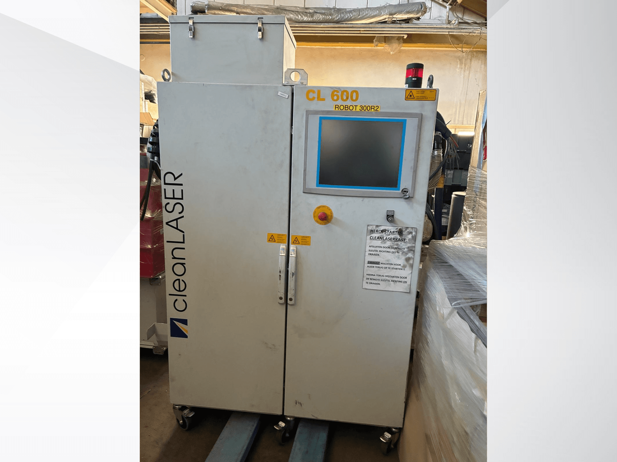„CLEAN LASER CL 600“ automatizavimo sistema, vaizdas iš priekio, su LCD ekranu, įspėjamosiomis etiketėmis ir valdymo mygtukais ant durelių.