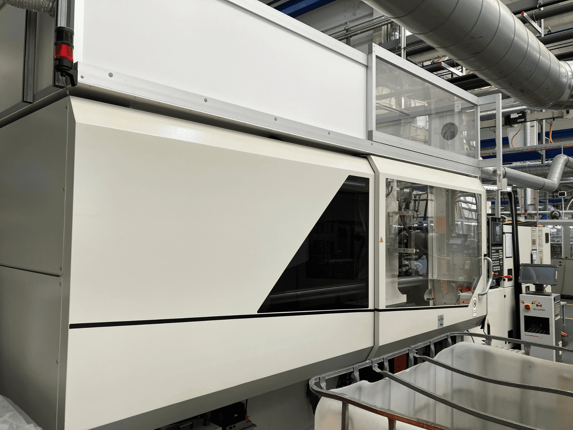 Pramoninės mašinos priekinis vaizdas, pasižymintis elegantišku baltu dizainu, ekrano skydeliu ir stikline sekcija komponentams matyti.