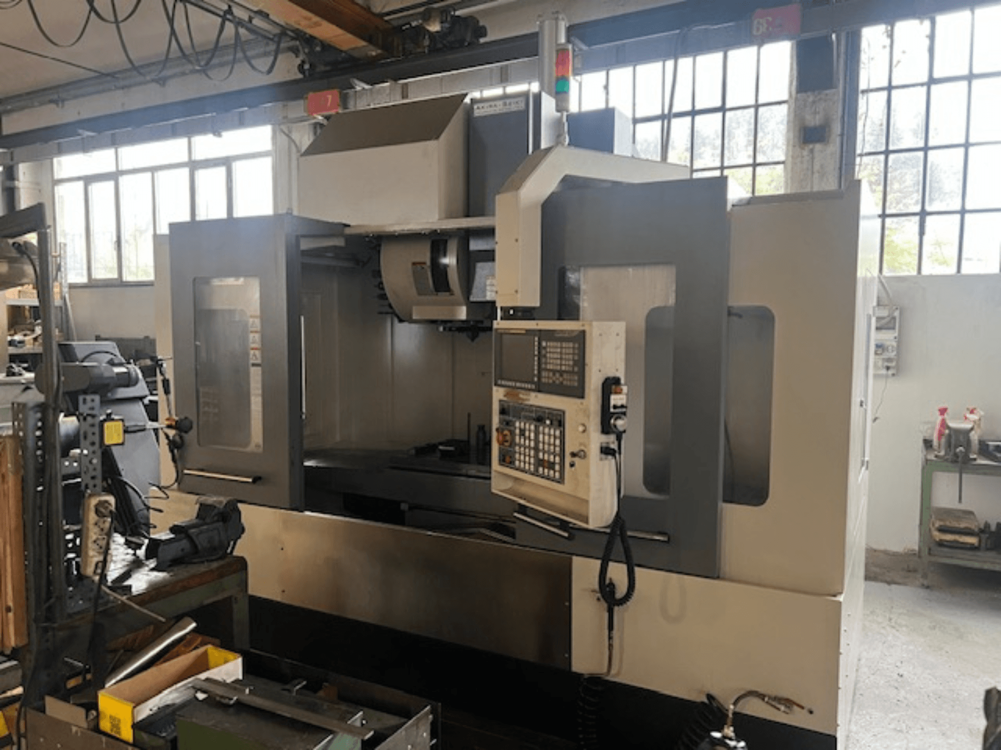 Aukštųjų technologijų CNC frezavimo staklės, vaizdas iš priekio, su skaitmeniniais valdikliais, pagrindiniais saugos indikatoriais ir kompaktiška konstrukcija.