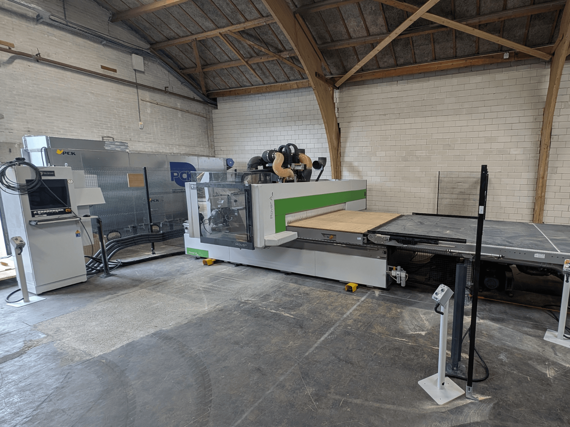 PCK CNC apdirbimo centras, vaizdas iš priekio, turi didelę pjovimo lova, valdymo skydelį, dulkių ištraukimo sistemą ir tvirtą konstrukciją.