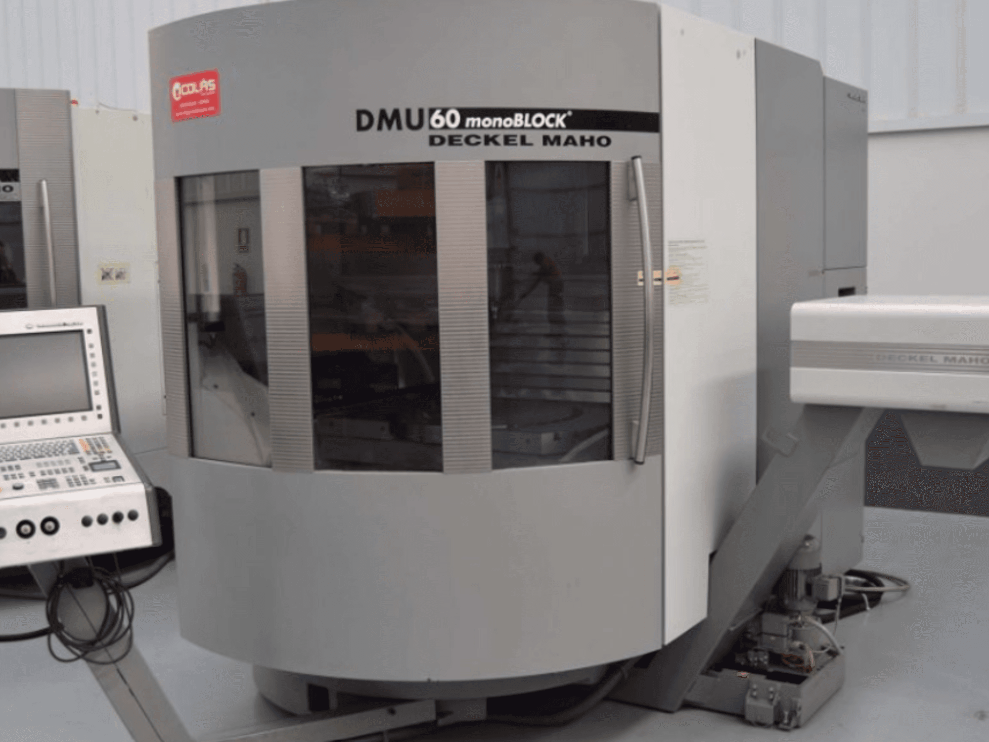 Vertikalusis apdirbimo centras „DMG DMU60 Monoblock“, vaizduojamas iš priekio, kairėje matomas valdymo pultas.