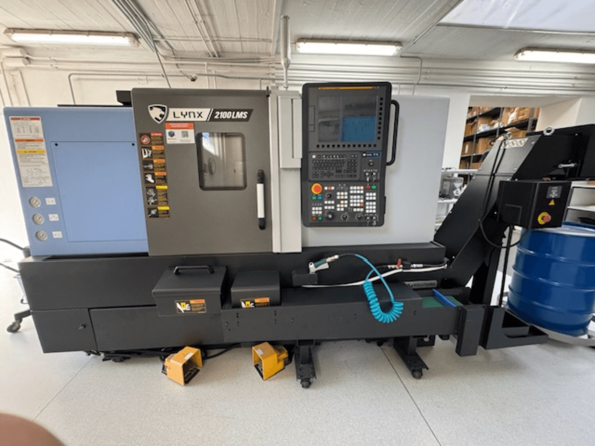 Horizontalios horizontalios tekinimo staklės DOOSAN LYNX 2100LMSA, vaizdas iš priekio, su valdymo skydeliu, aušinimo skysčio žarna ir laikymo dėžėmis.
