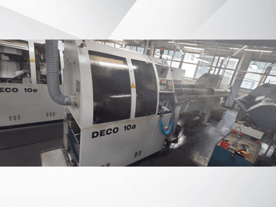 DECO 10a CNC staklės dirbtuvėse, matomas priekinis vaizdas, valdymo skydelis ir išmetimo sistema. Pasižymi tvirta konstrukcija ir tiksliais įrankiais.